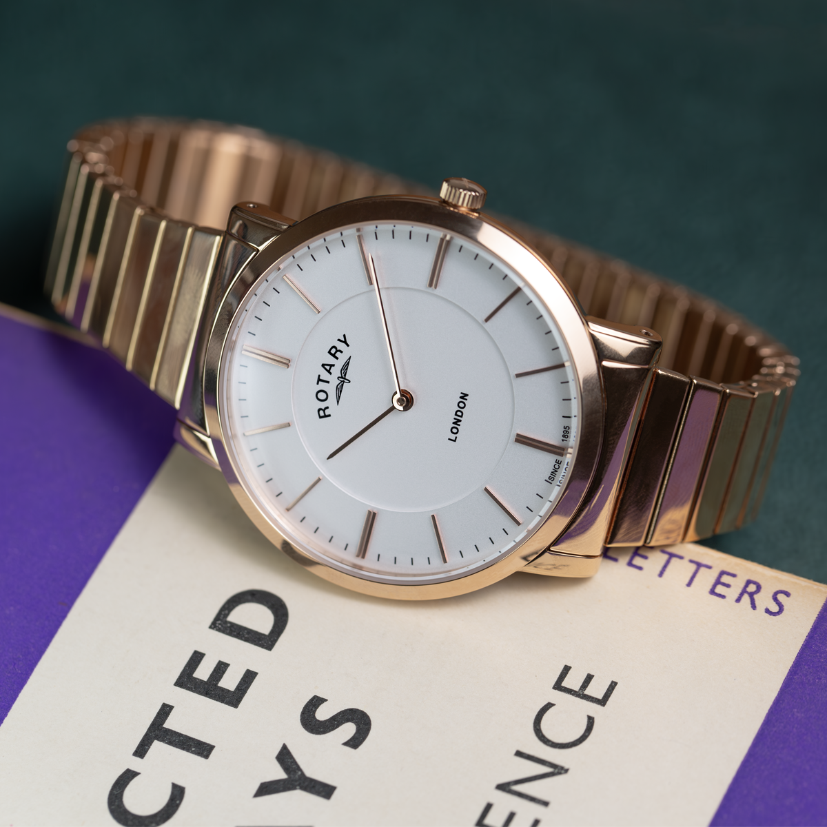 Rose gold watch with white face on a purple and white book