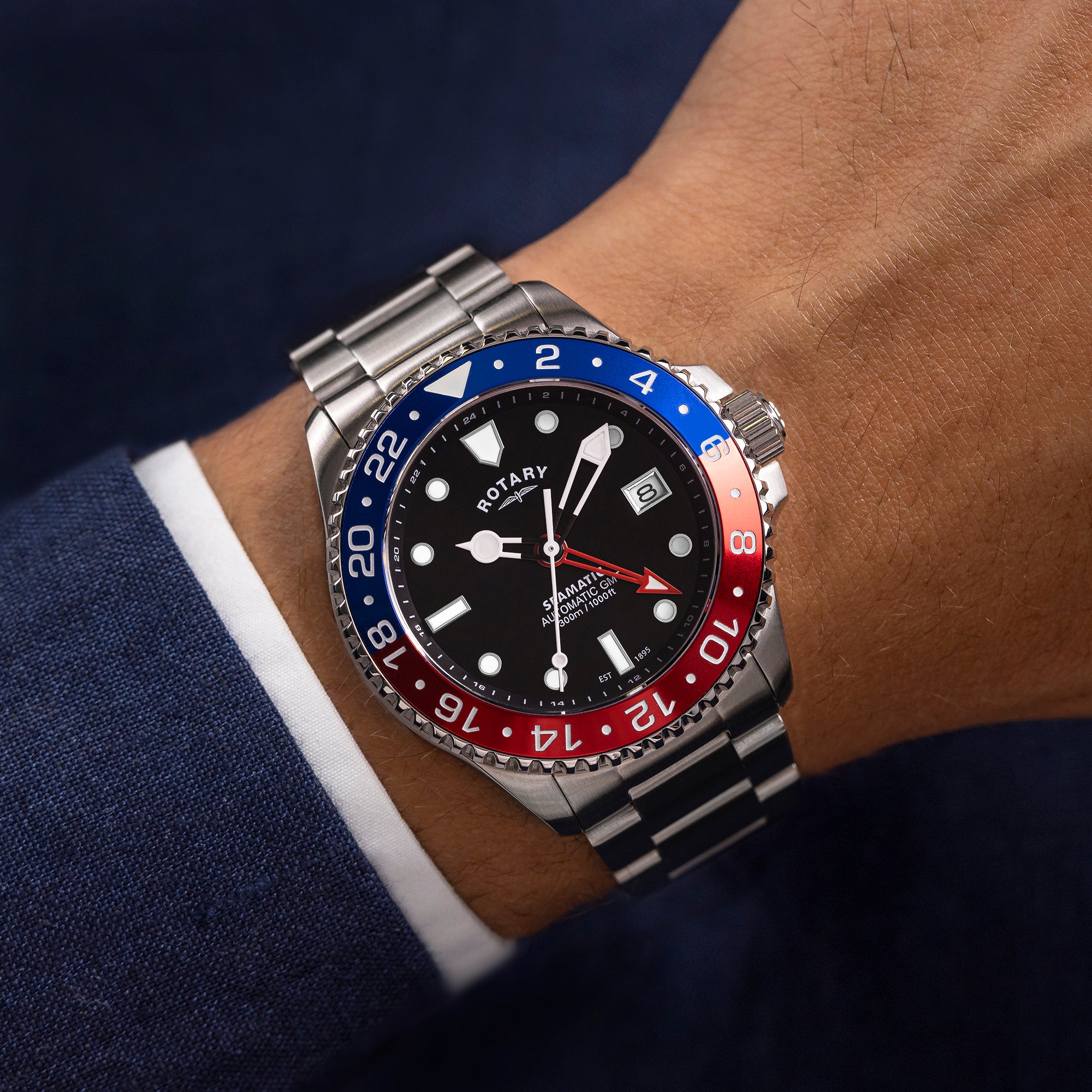 Close-up of a wrist wearing a Rotary Seamatic GMT watch with a blue and red bezel.