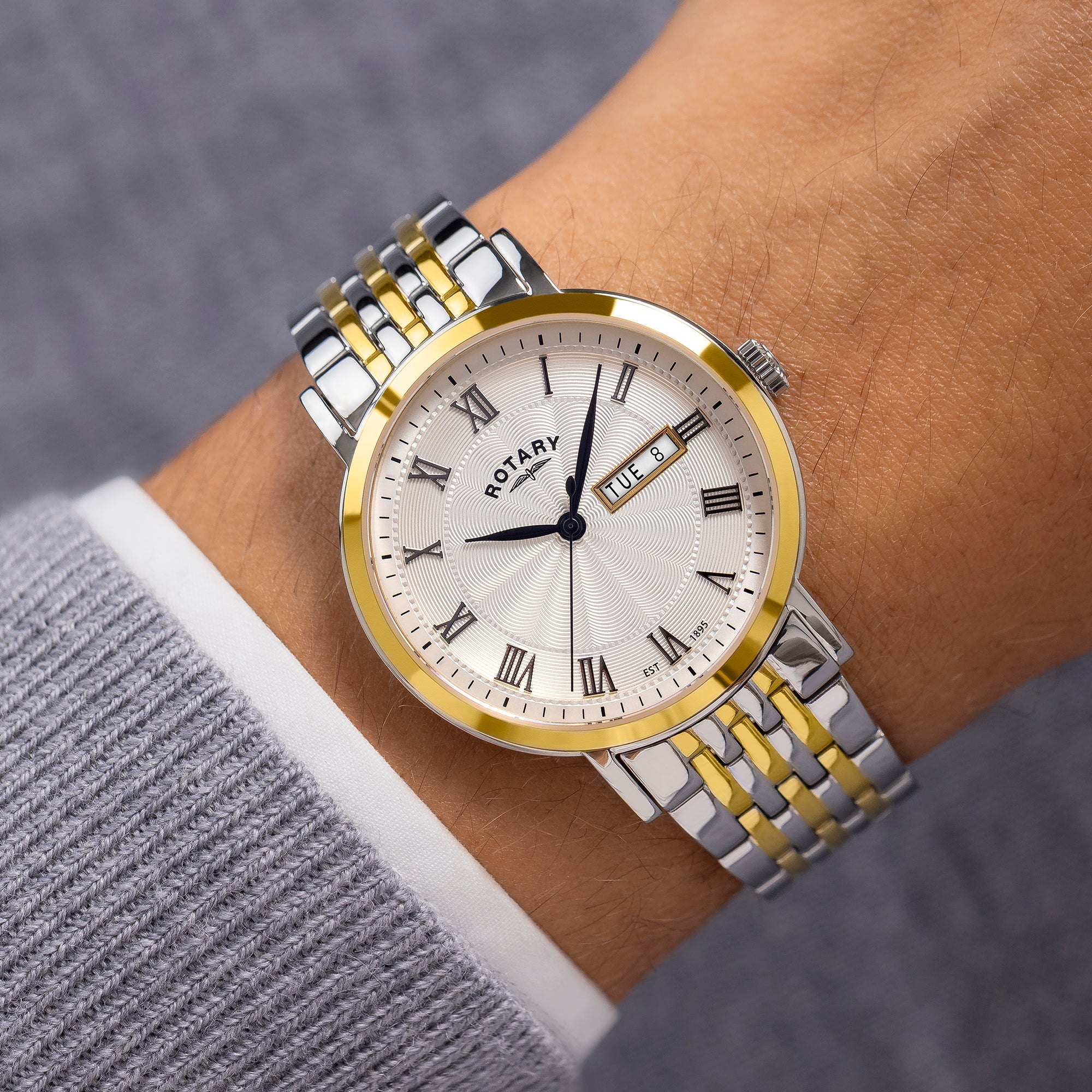 Rotary two tone watch on a wrist with a grey background
