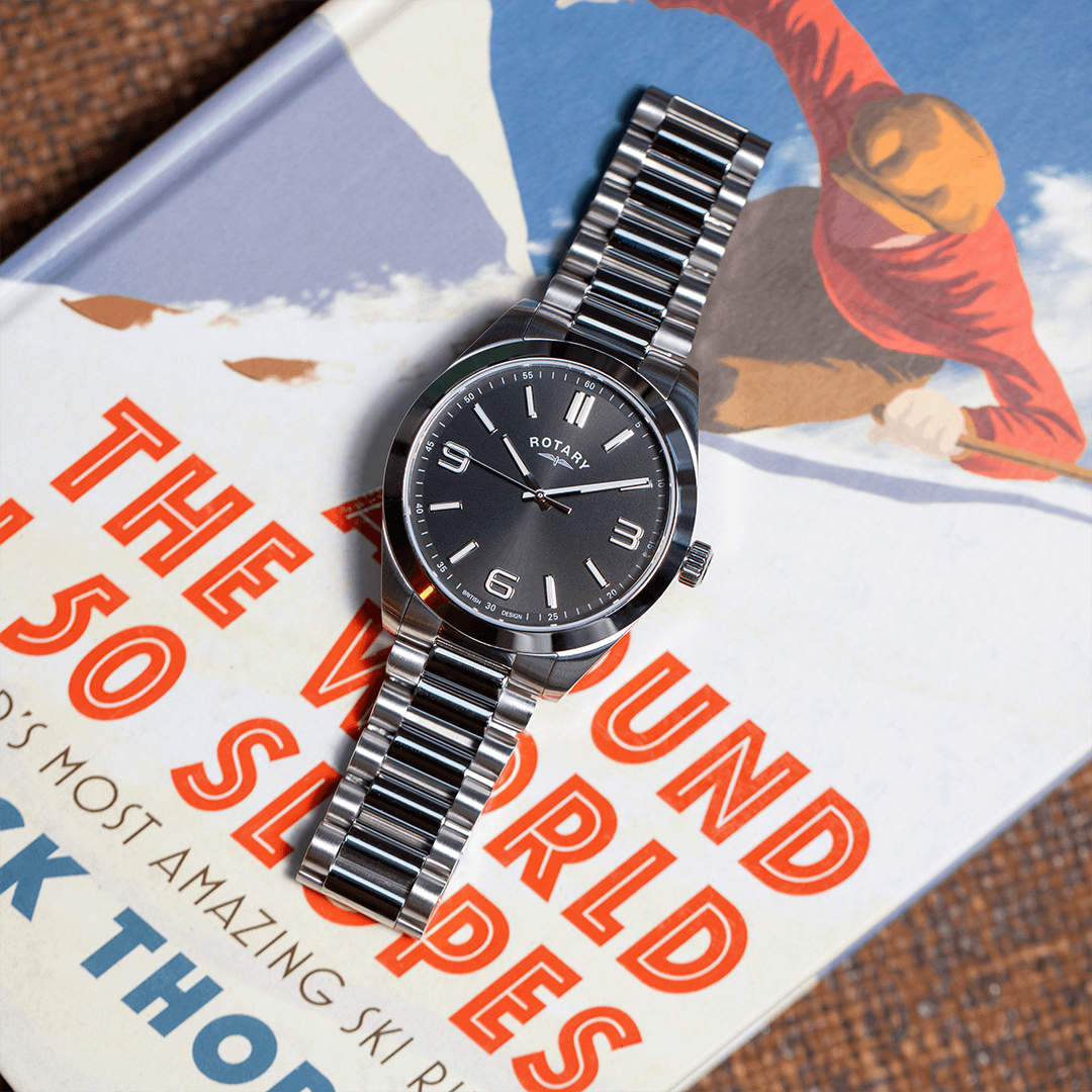 Rotary Sport watch in stainless steel with a black dial pictured on a book