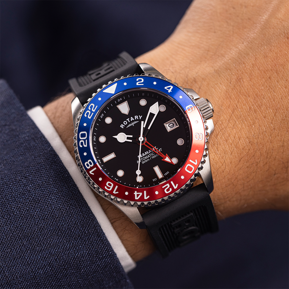 Close-up of a wrist wearing a Rotary Seamatic watch with a black, blue, and red bezel.