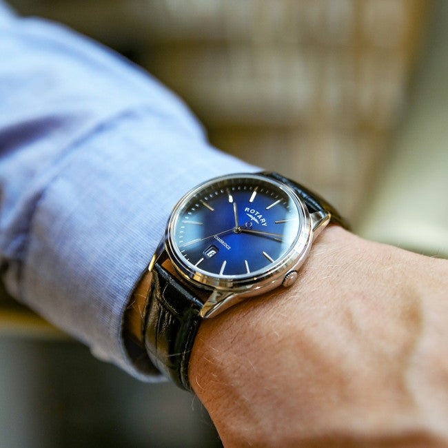 A man wearing a rotary watch with a blue dial and stainless steel case