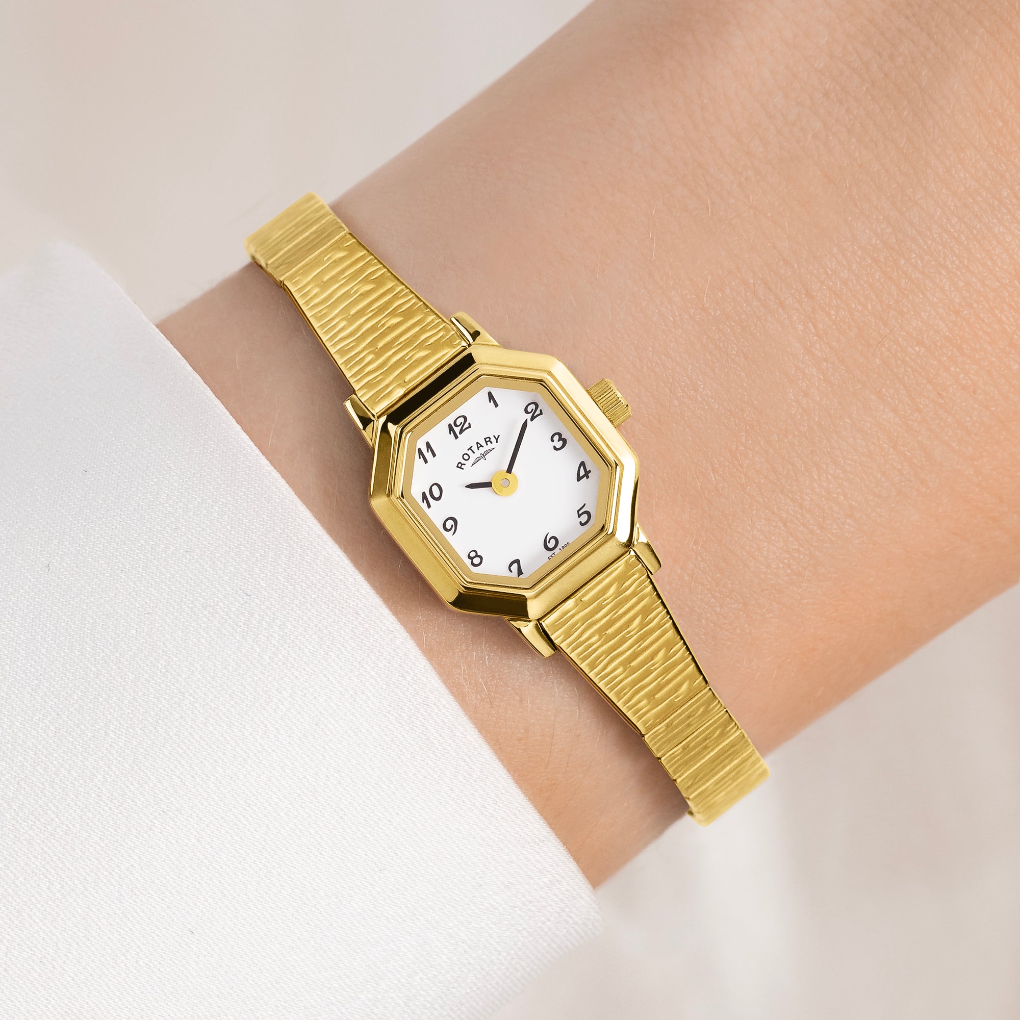 Gold Rotary wristwatch on a wrist with a white background