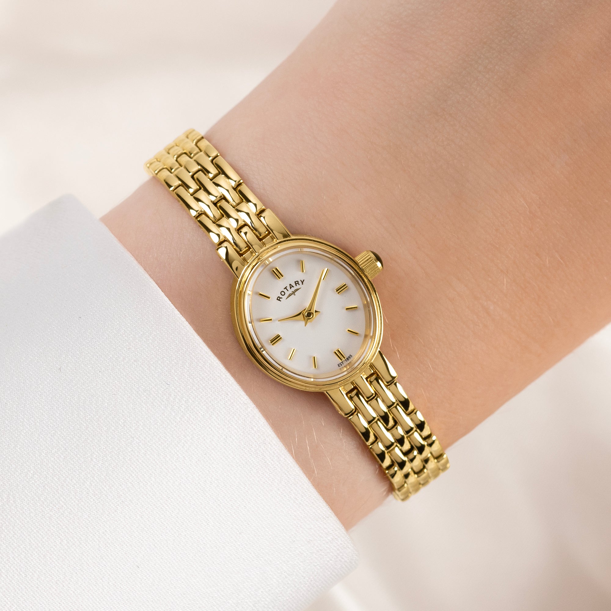 Rotary Gold watch with a white face on a wrist against a light background