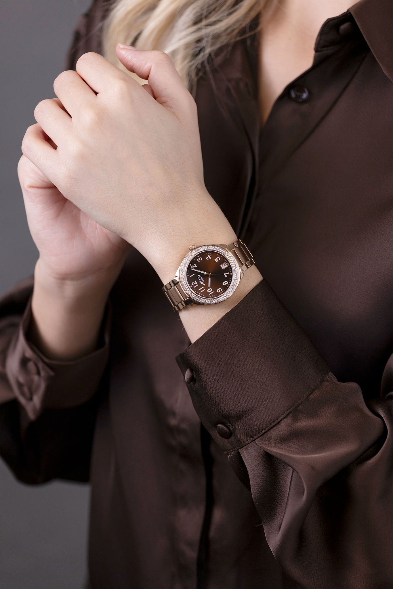 Woman wearing a brown shirt and a Rotary Brilliance watch with a blurred background