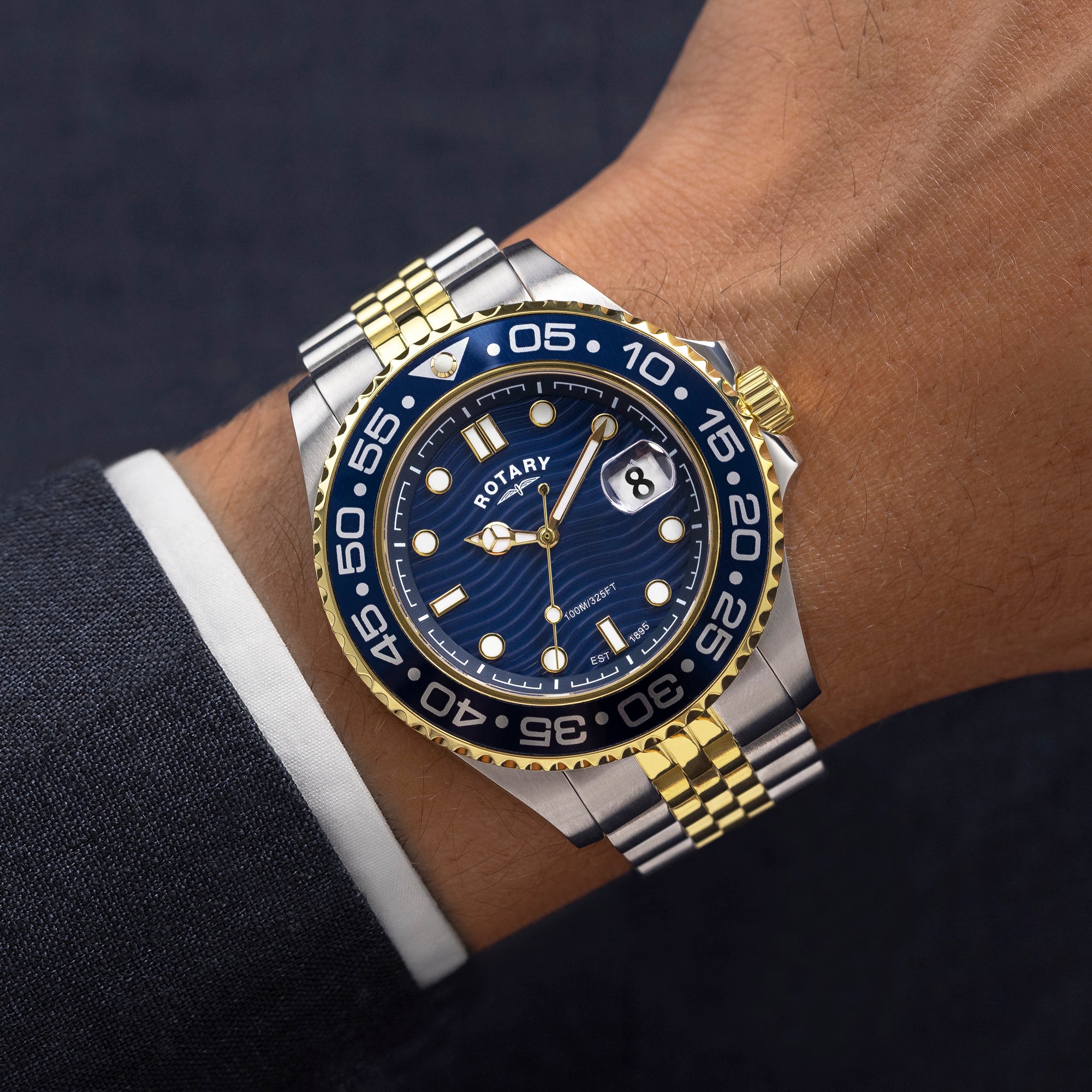 Luxury watch with blue dial and gold accents on a wrist against a dark background