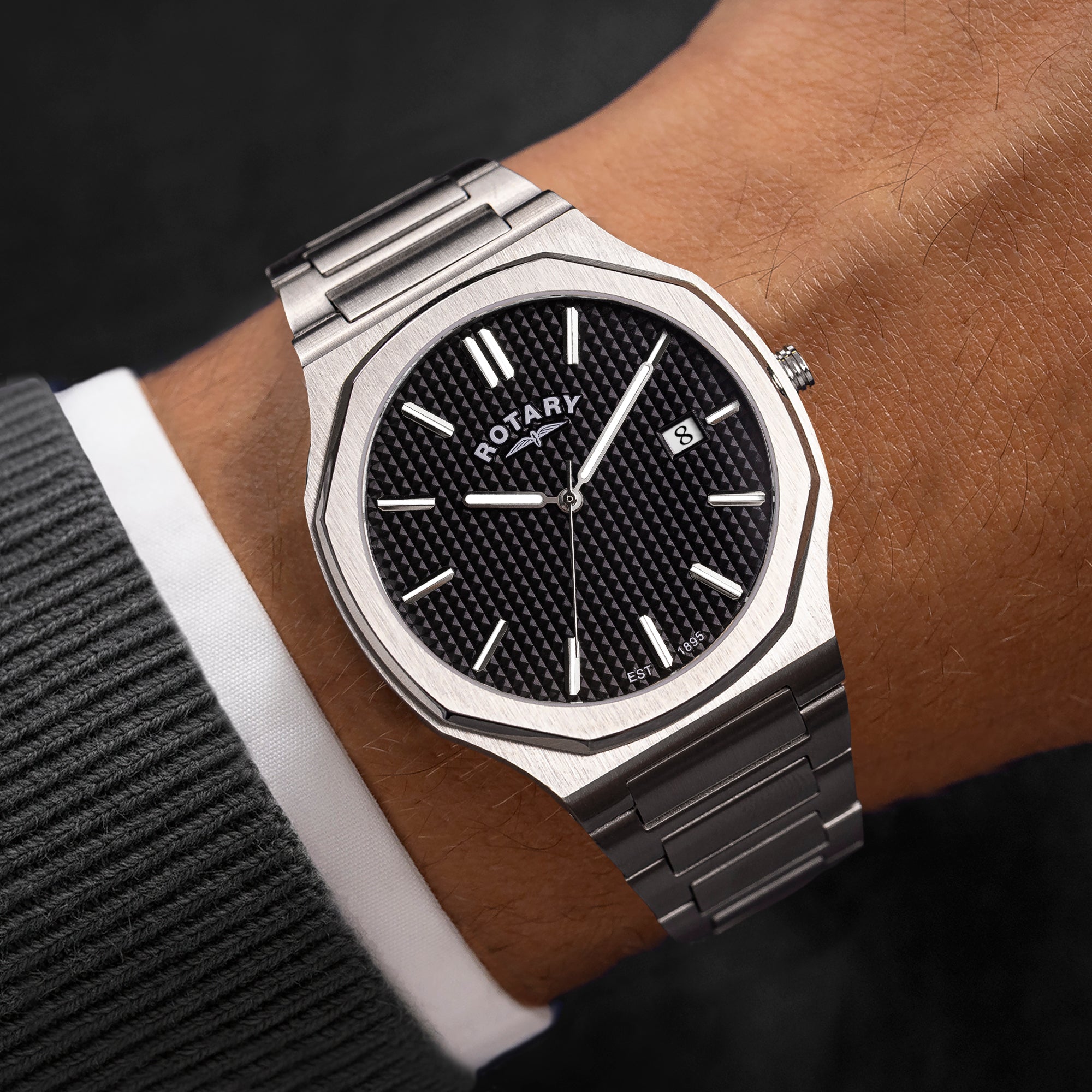 Silver rotary watch on a wrist with a black face