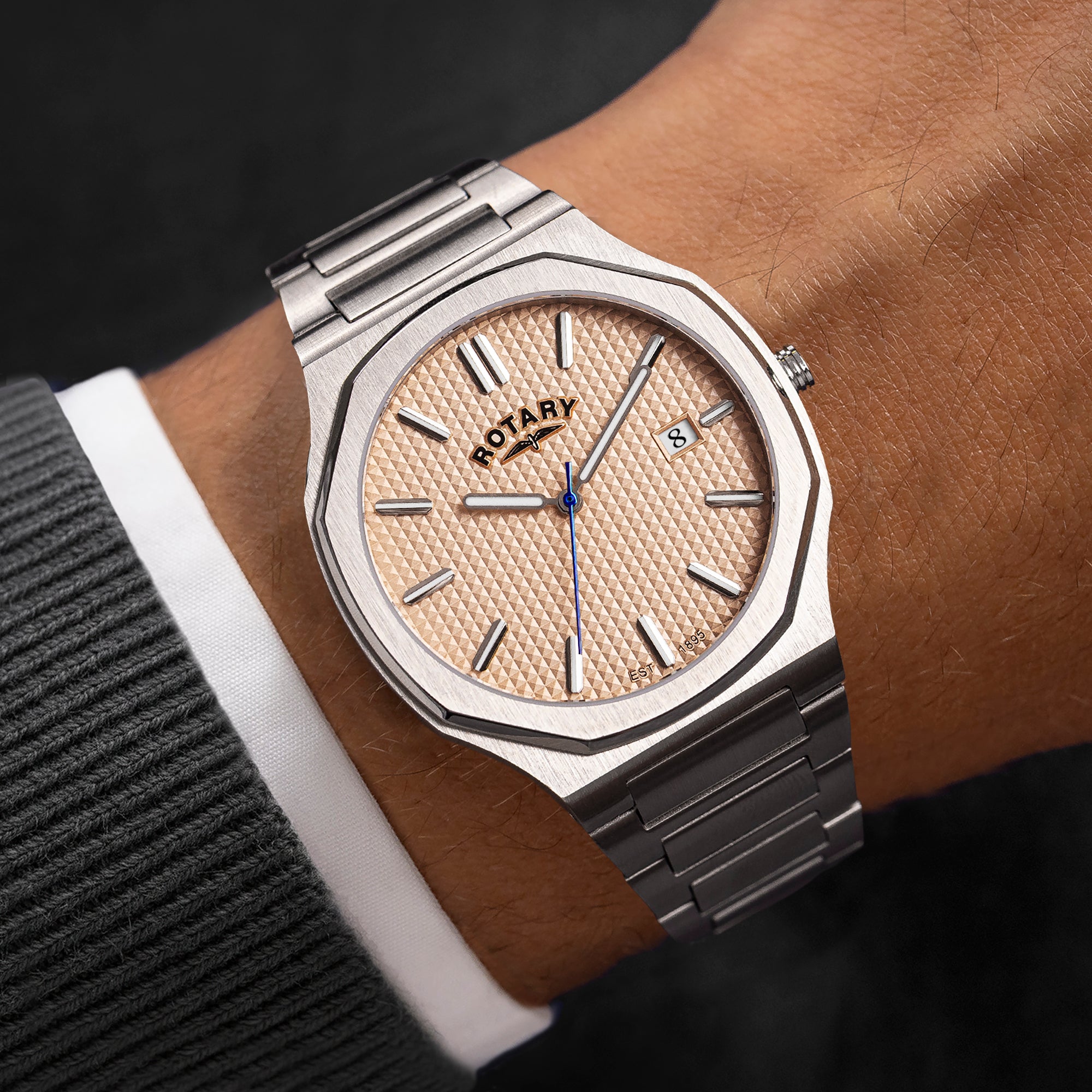 Close-up of a wrist wearing a silver Rotary watch with a beige face.