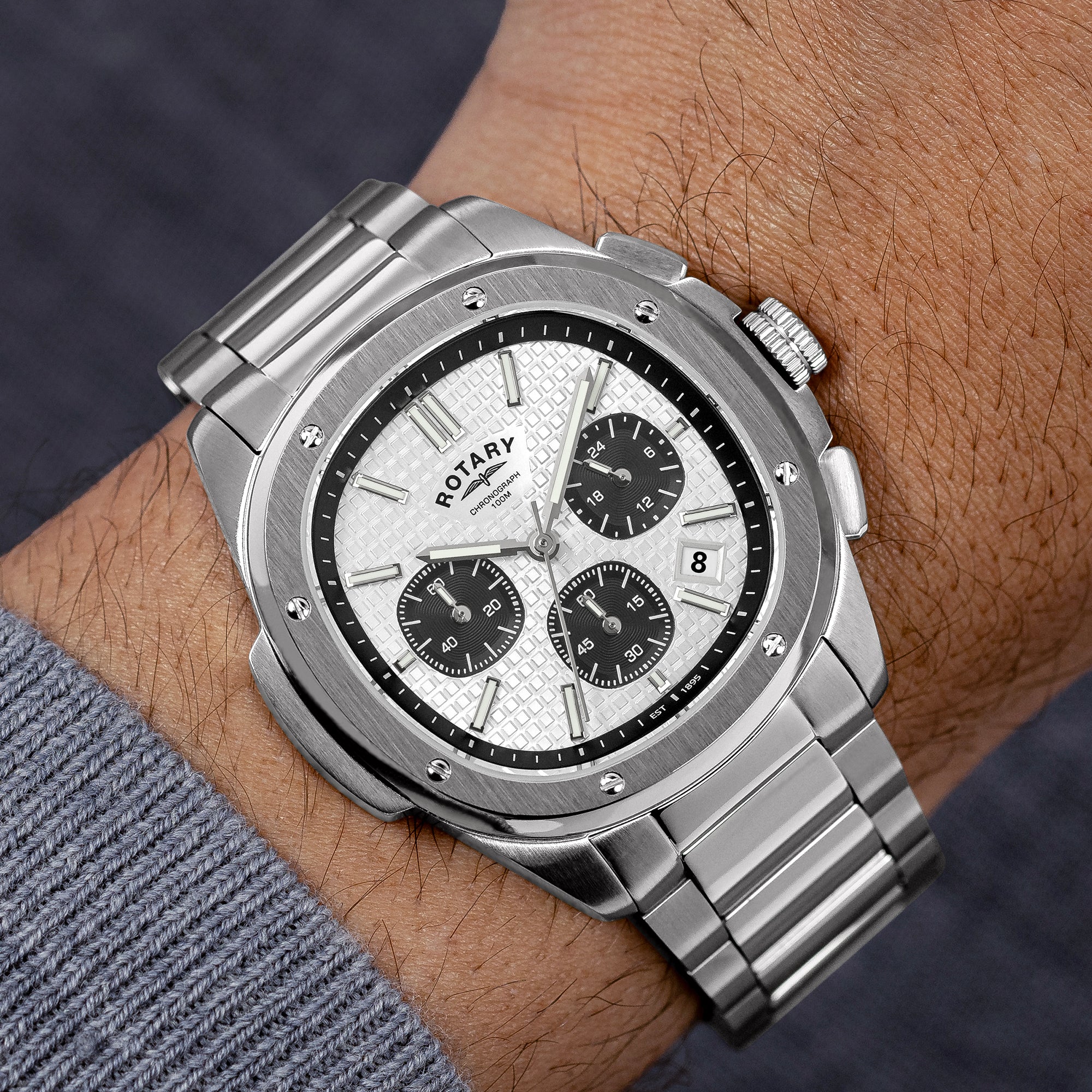 Silver Rotary Apex100 Chronograph watch on a wrist with a dark background