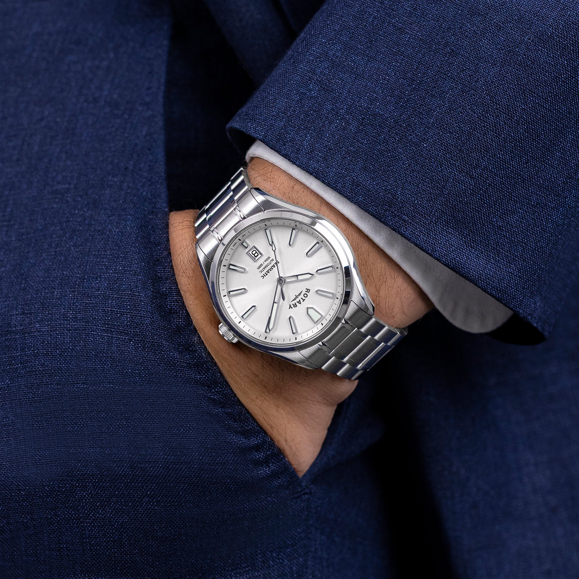 Silver Rotary Seamatic 100 watch on a man's wrist with a blue suit background