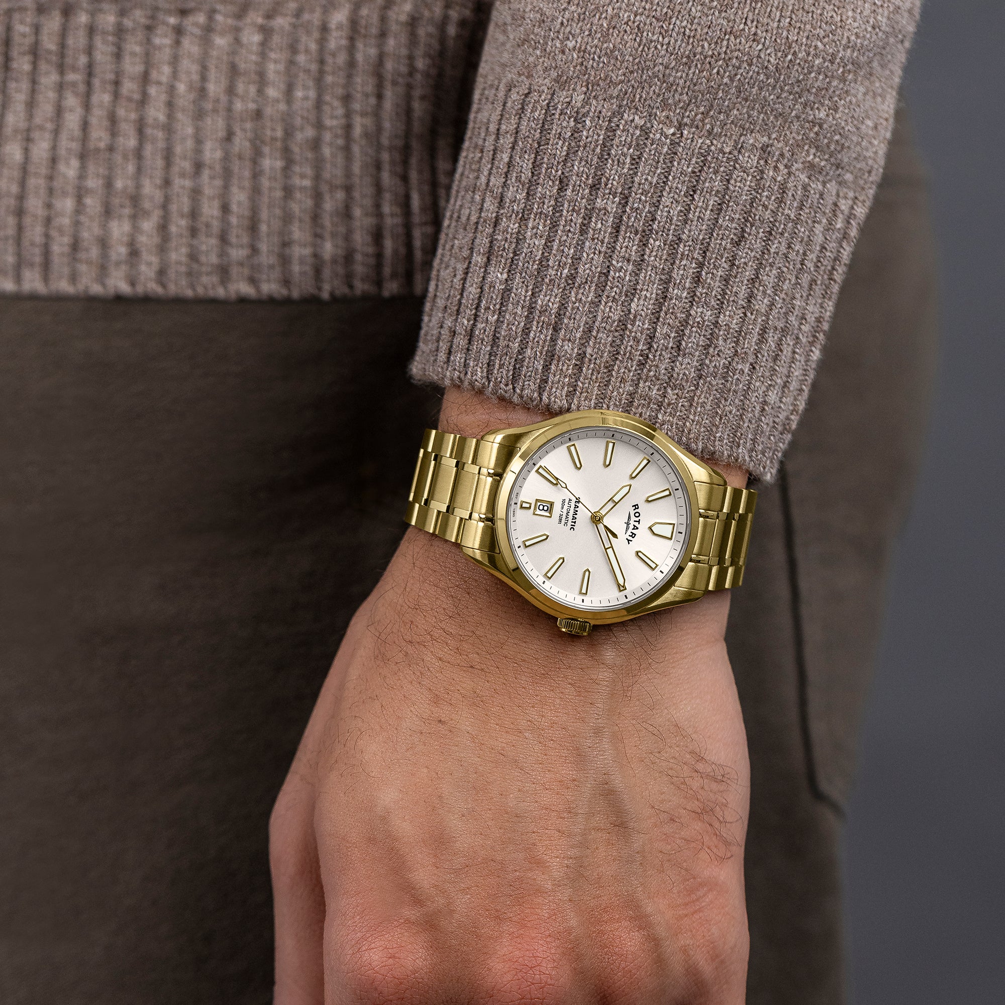 Gold Rotary Seamatic 100 wristwatch on a man's wrist with a neutral background