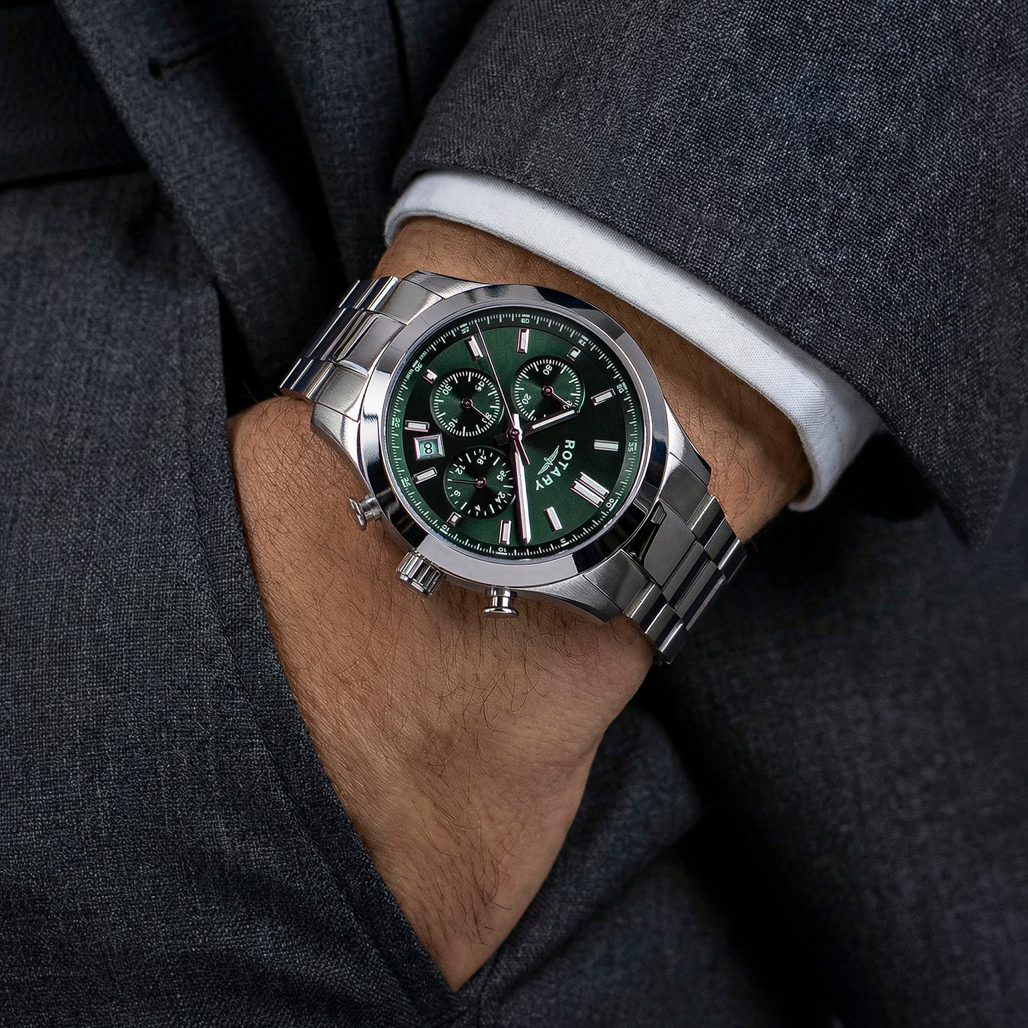 Close-up of a man wearing a silver Rotary Heritage Chronograph watch with a green face on a dark suit background