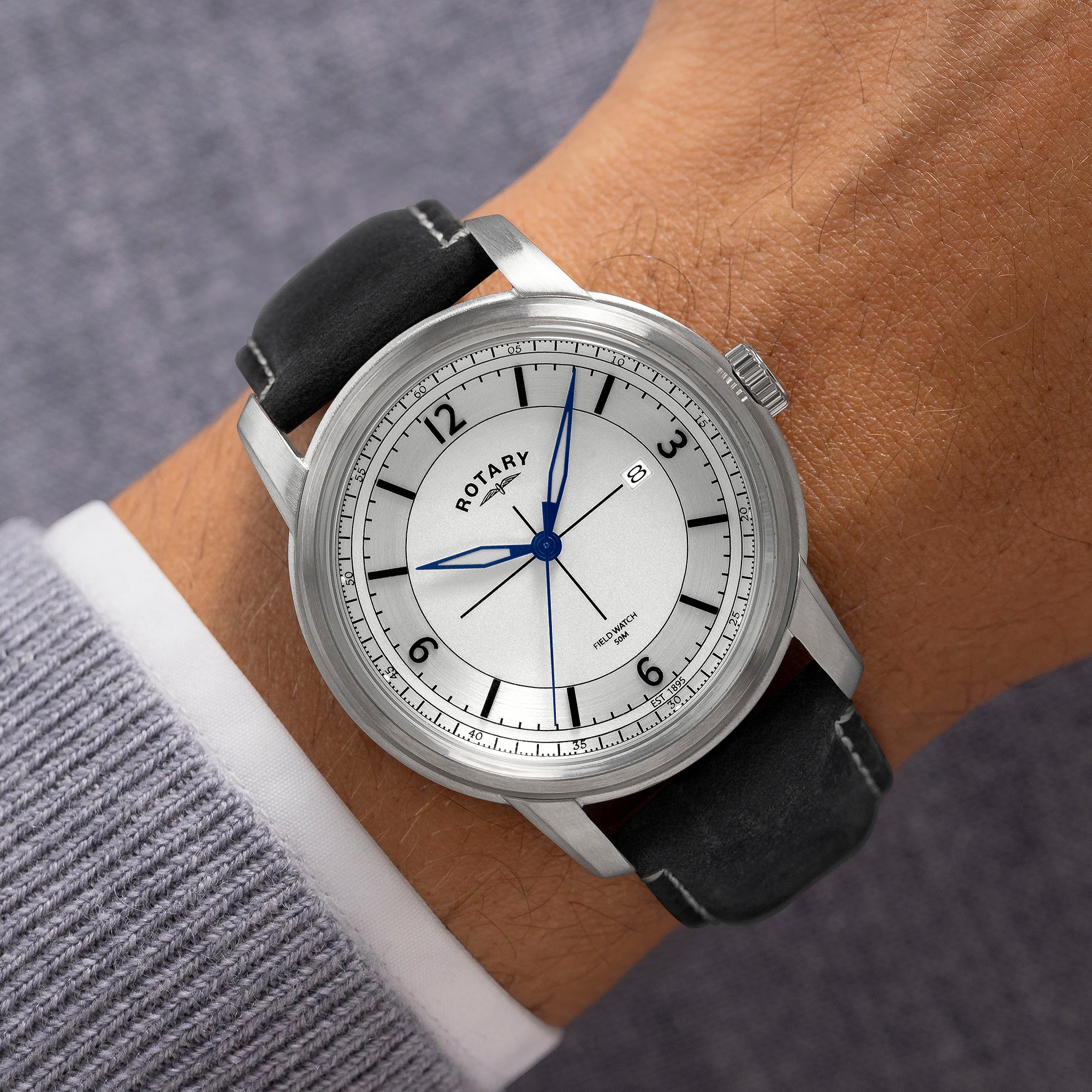 Rotary Field watch on a wrist with a gray background