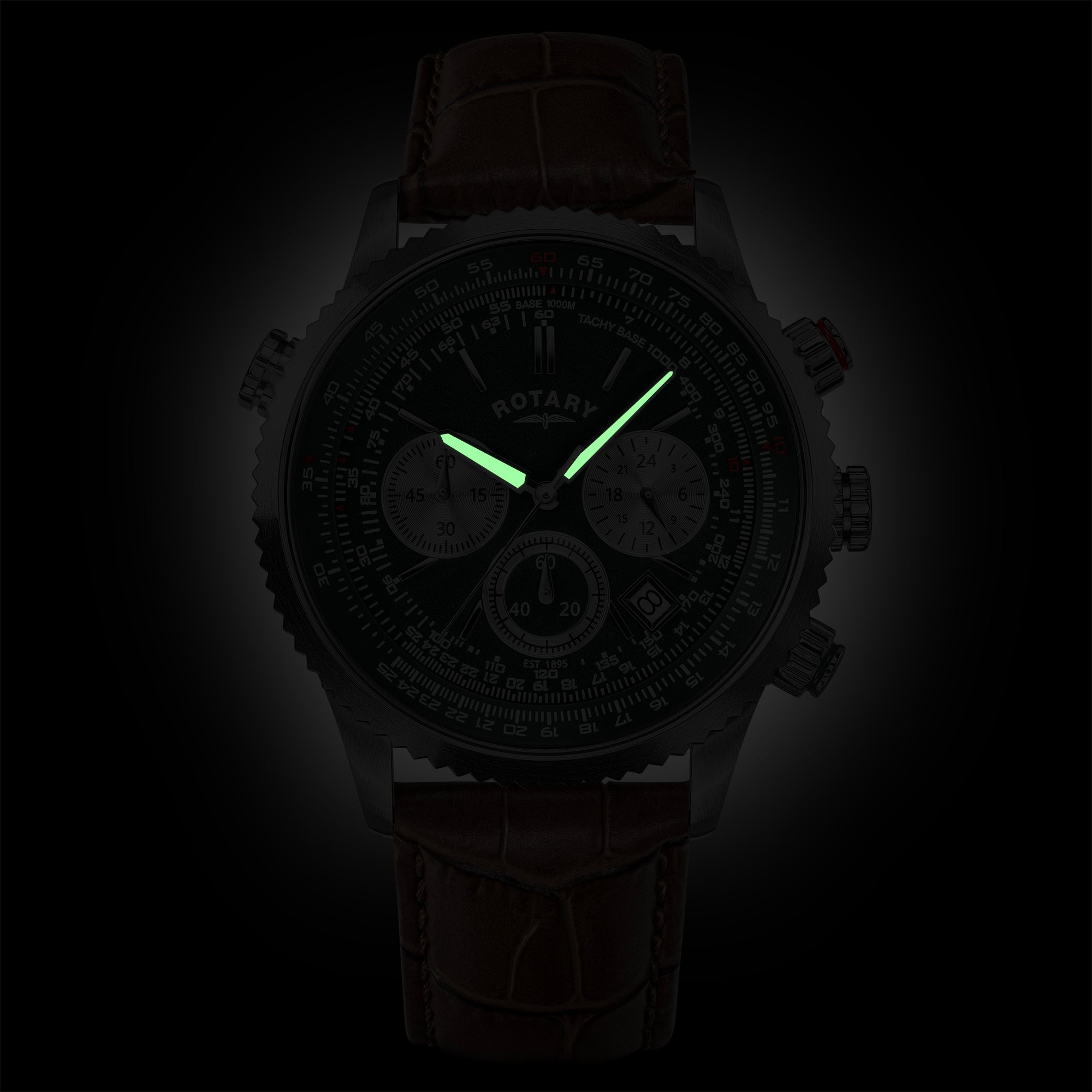 A dark chronograph watch with a brown leather strap, black dial, and glowing green hands, shown against a black background.