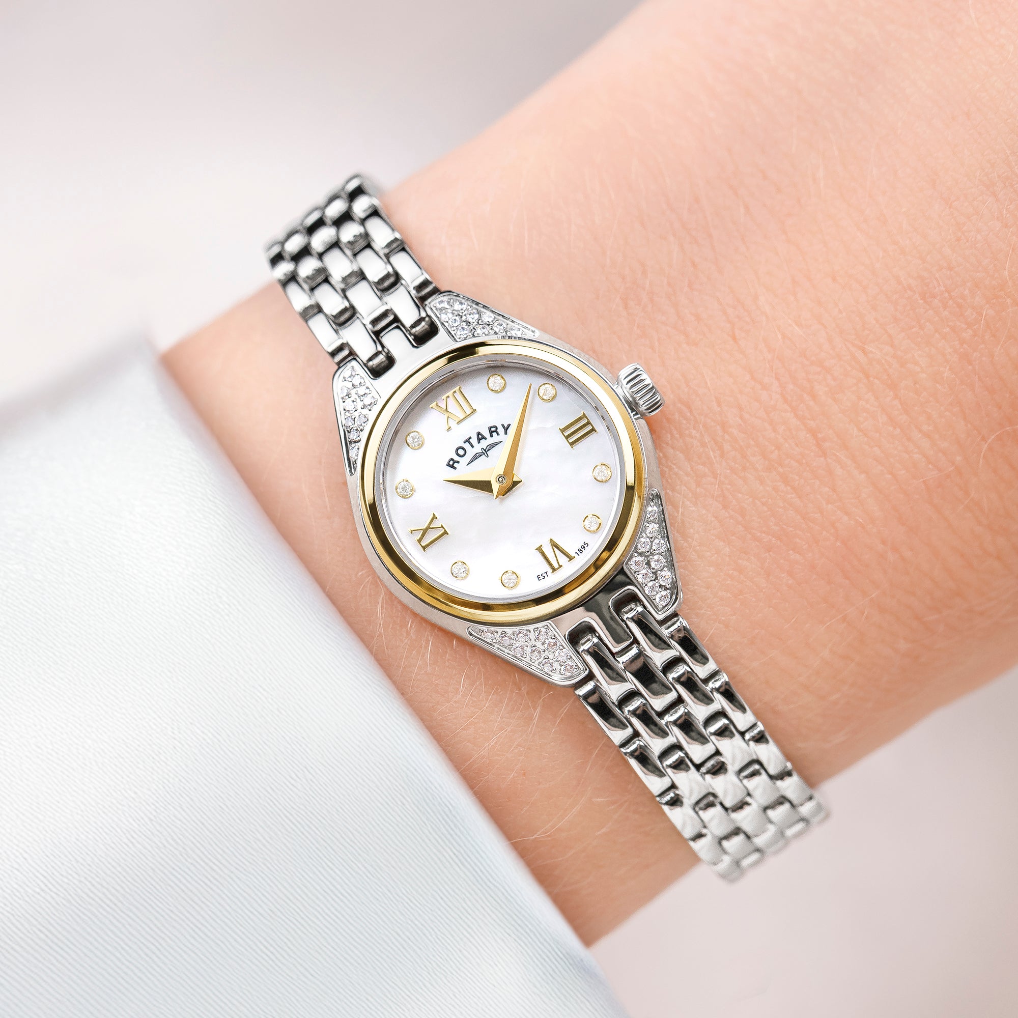 Silver and gold Rotary cocktail watch on a wrist with a white background