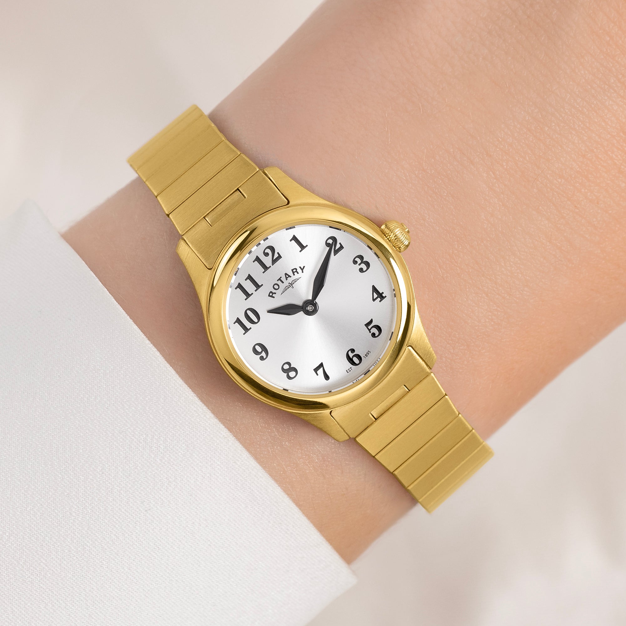 Gold Rotary watch on a wrist with a white background
