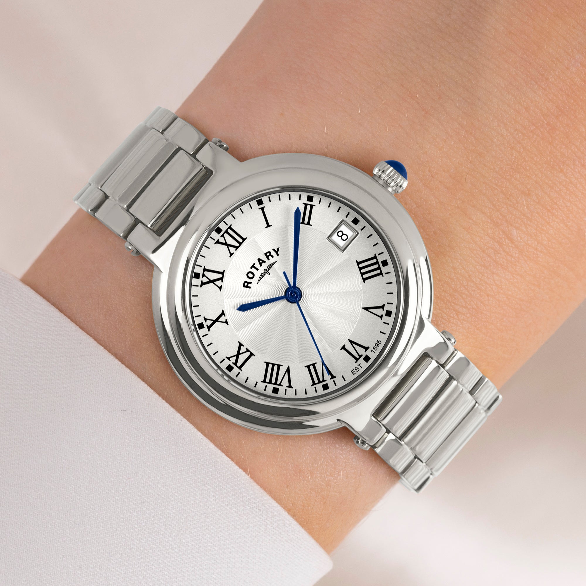 Silver rotary watch on a wrist with a light background