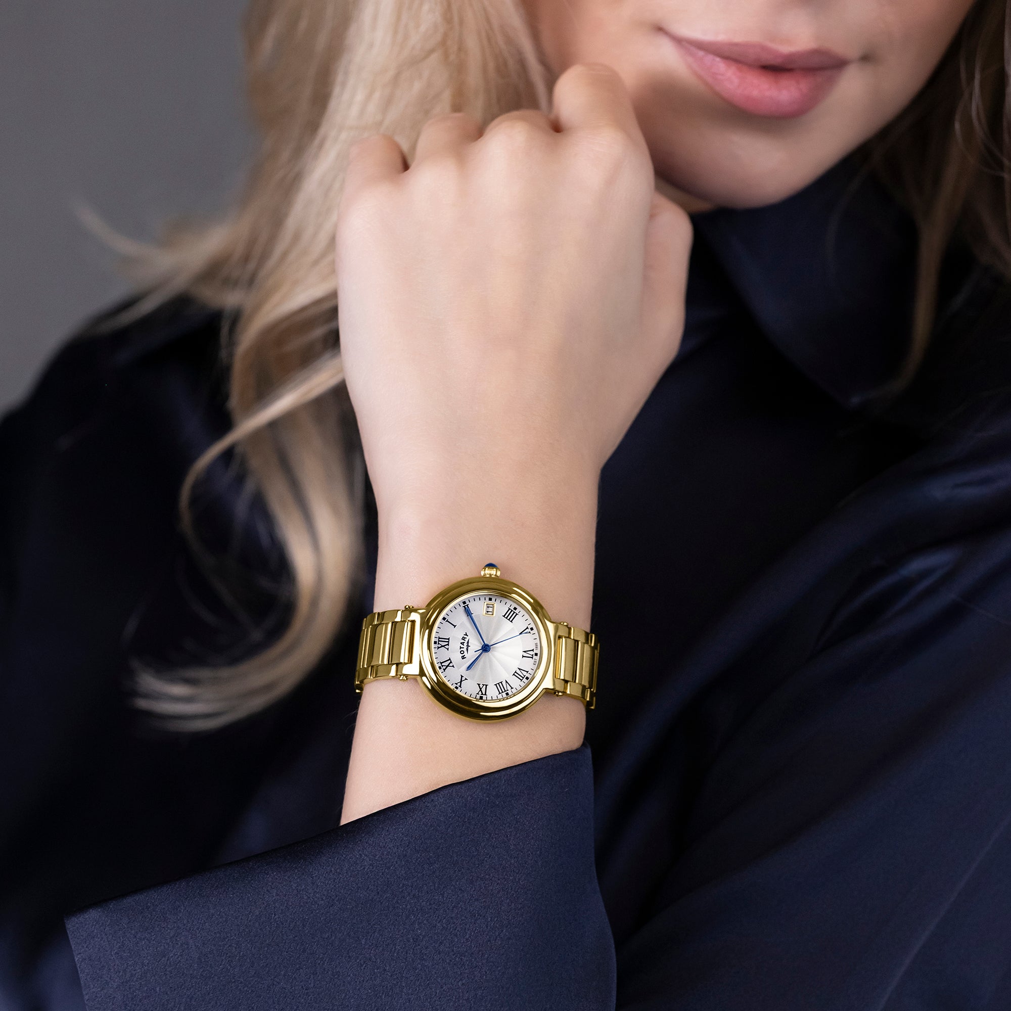 Gold Rotary watch on a woman's wrist with a dark background