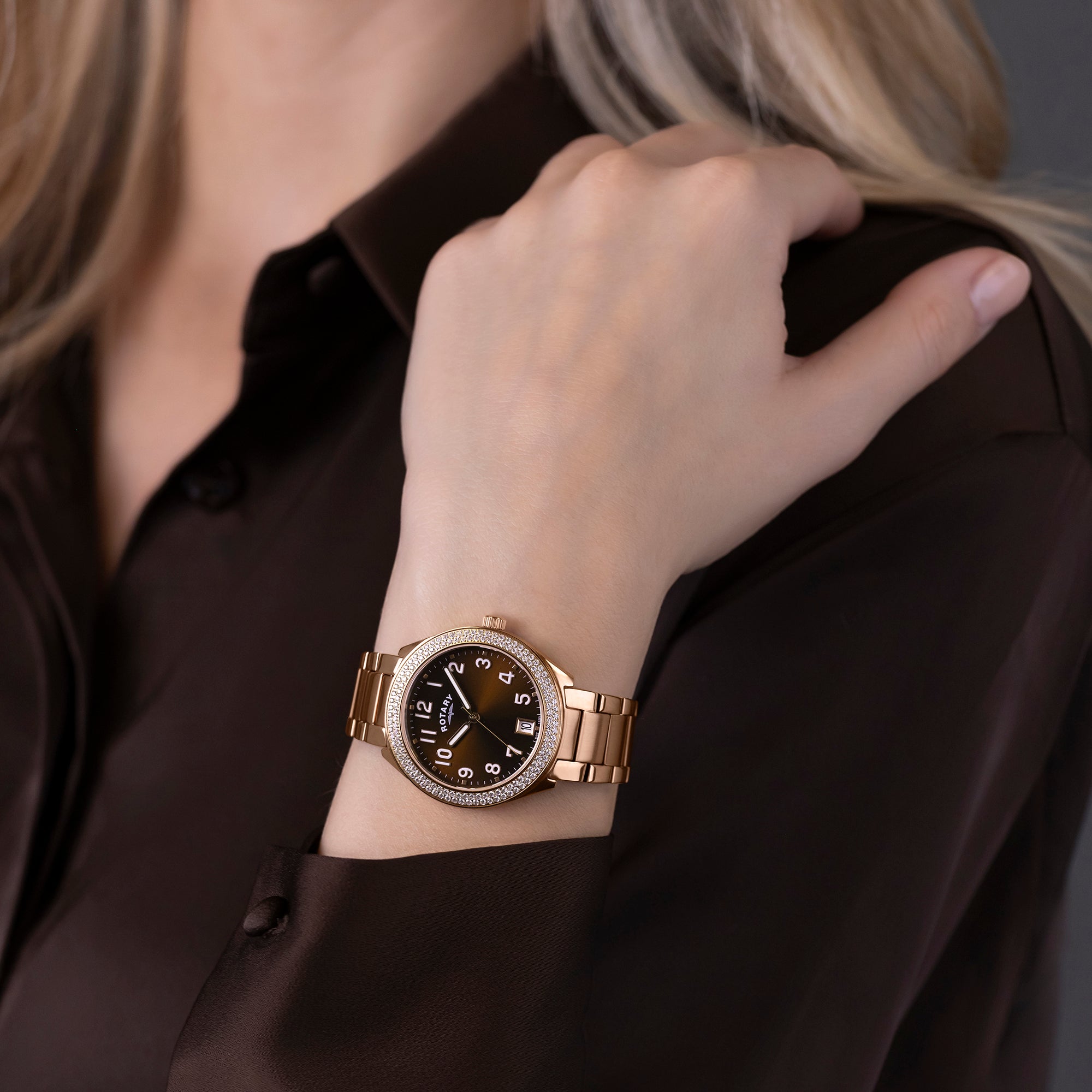 Rose gold Rotary Brilliance watch on a person's wrist with a blurred background