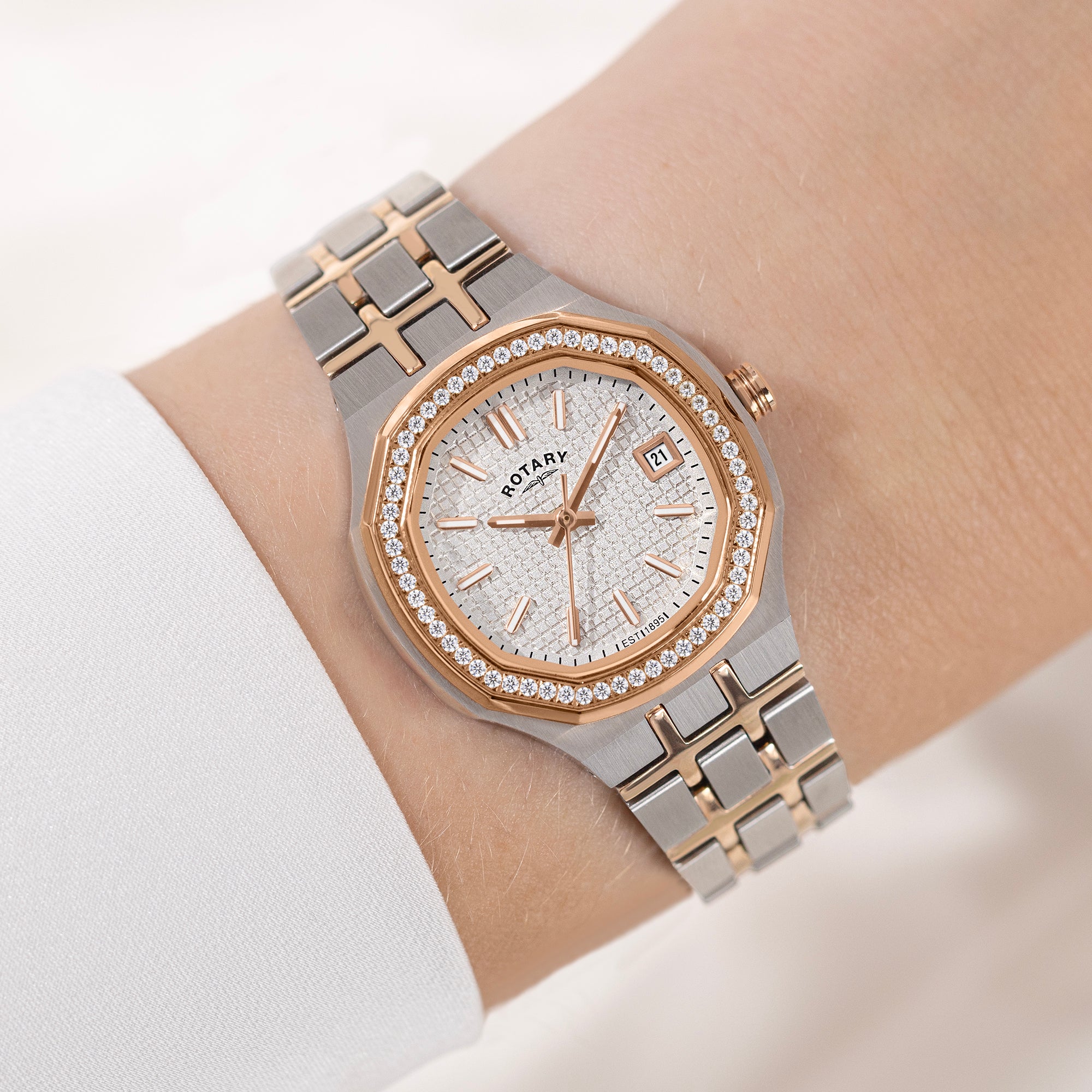 Luxury watch with a silver and rose gold band on a wrist against a neutral background