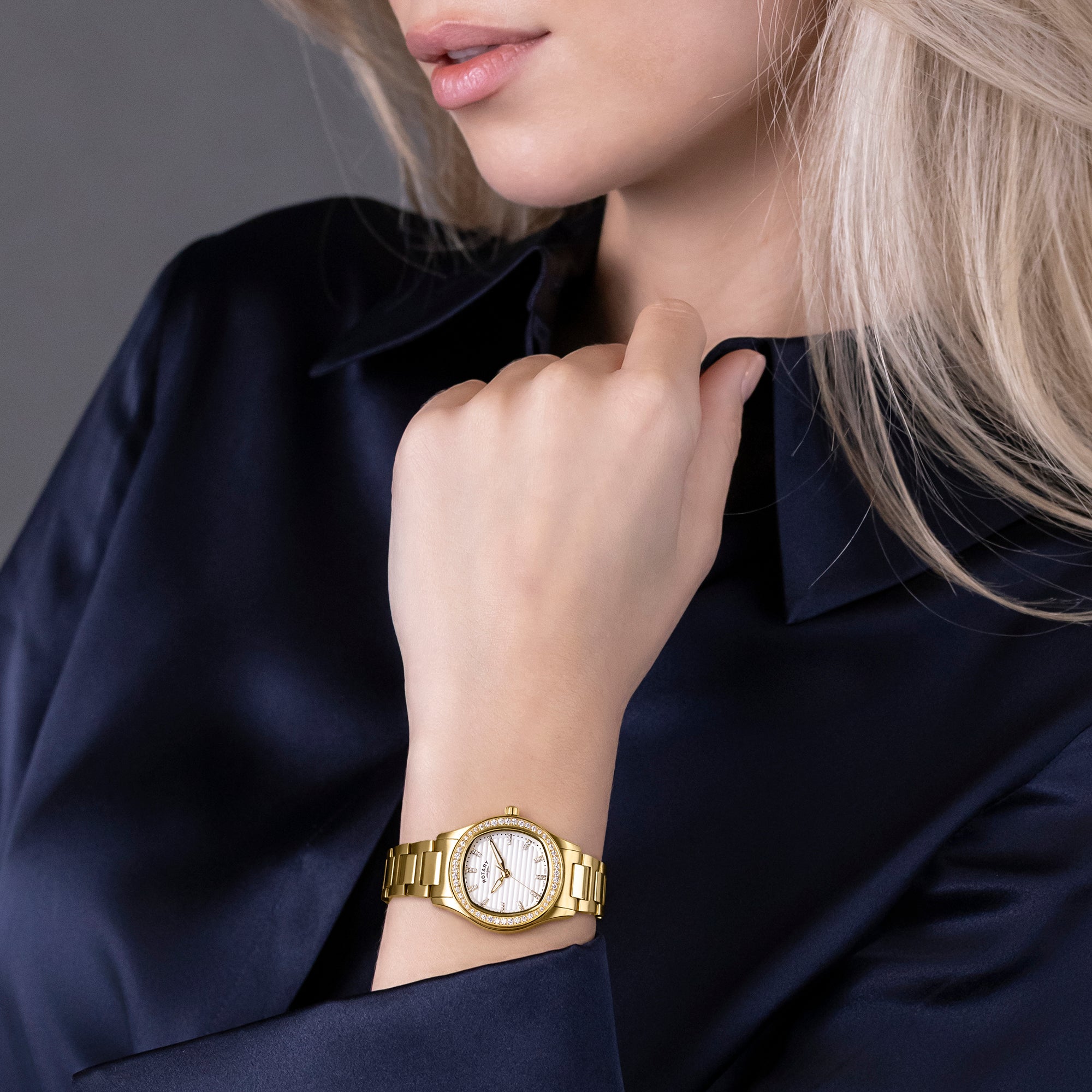 Woman wearing a gold Rotary Brilliance watch on a dark background