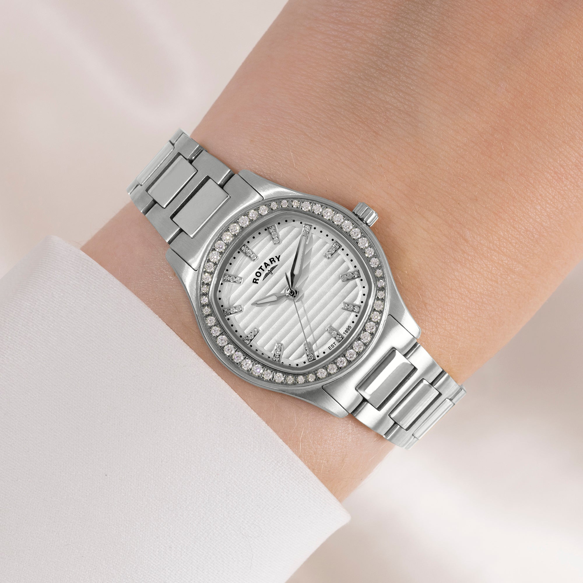 Silver Rotary wristwatch with gemstone accents on a wrist against a light background