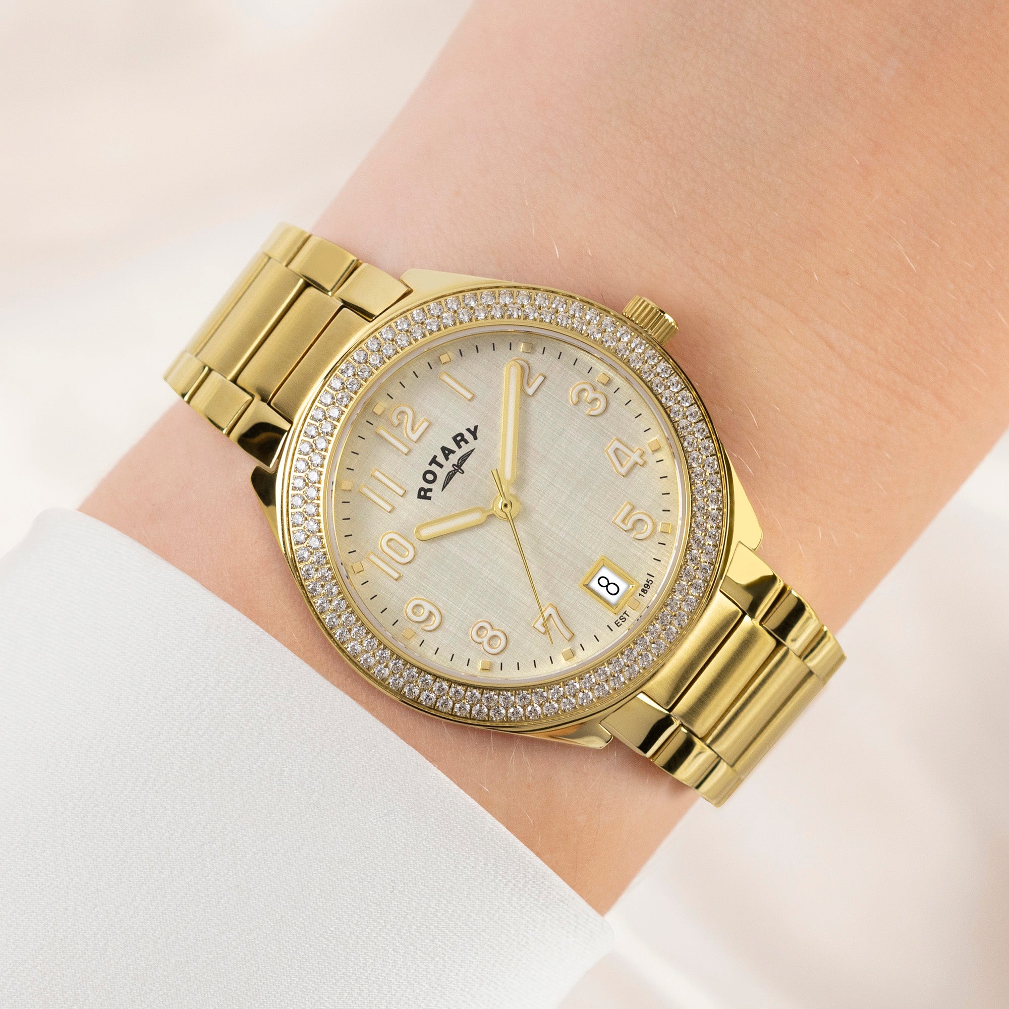 Rotary Brilliance Gold wristwatch with gem stone accents on a wrist against a light background