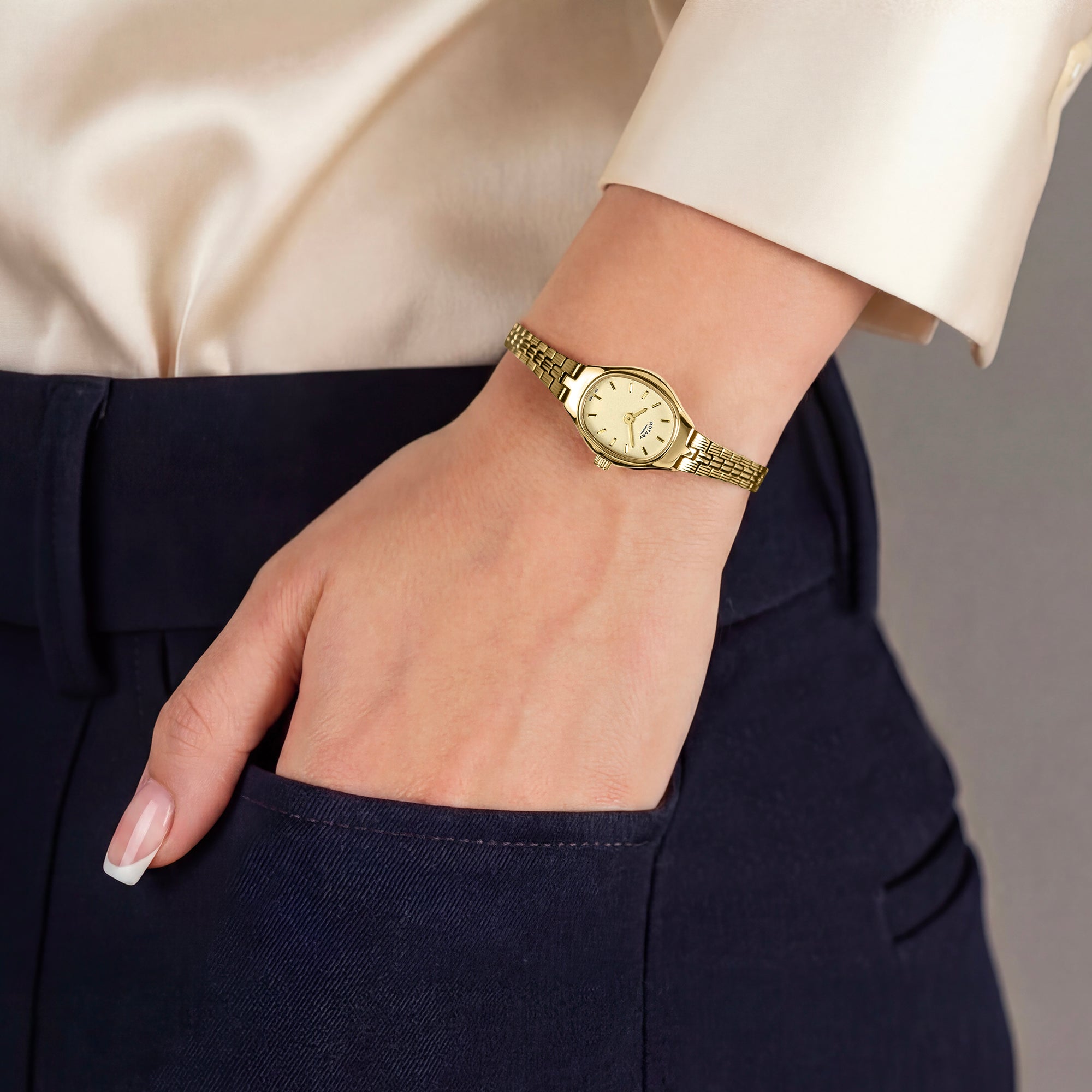 Gold Rotary wristwatch on a woman's wrist with a neutral background