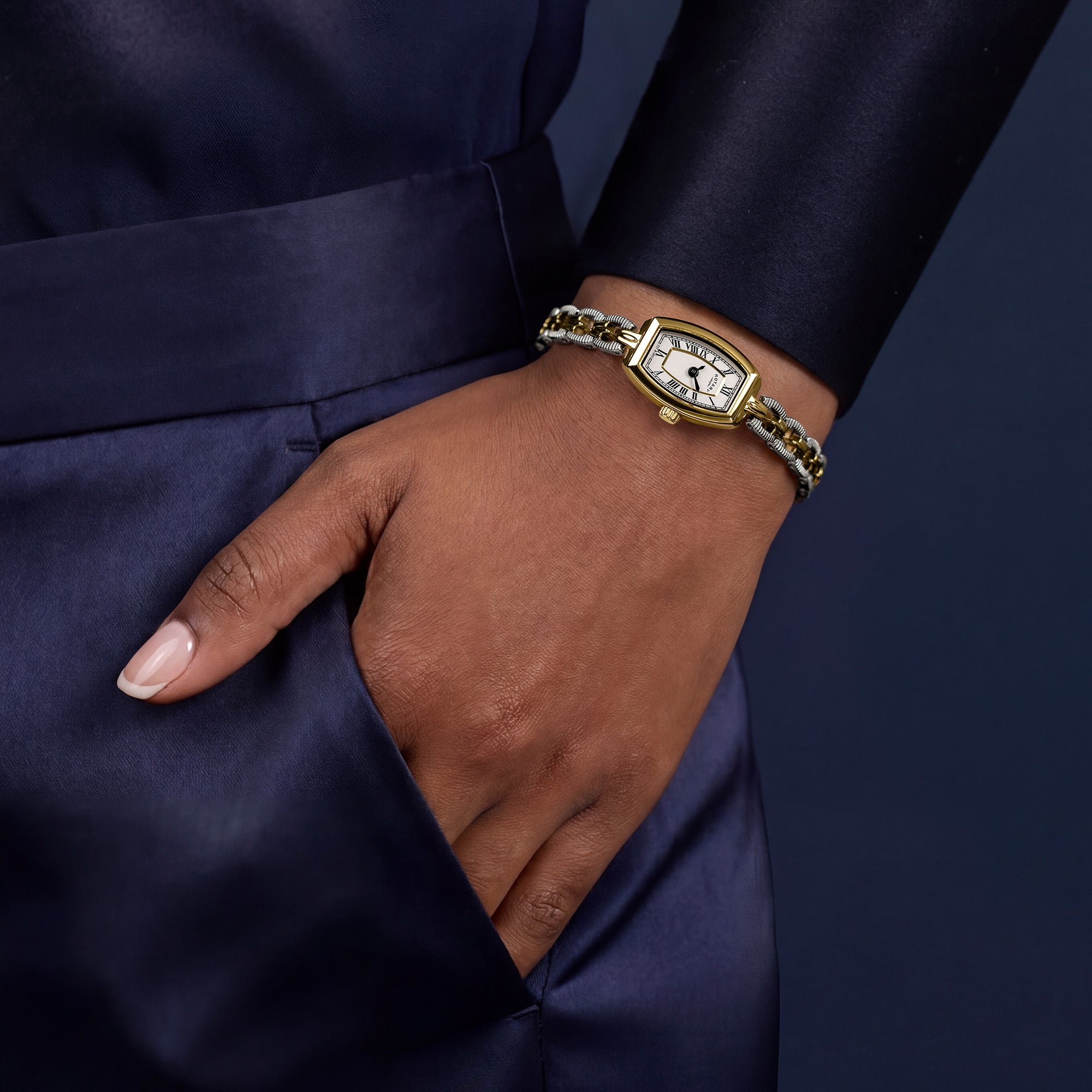 Women's hand wearing a two-tone Rotary watch on a dark background