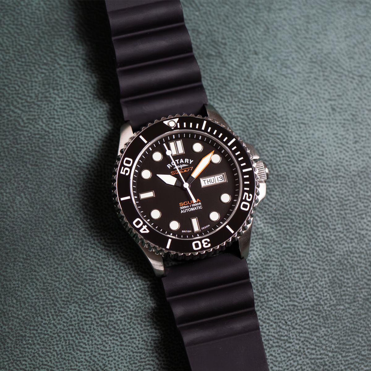 Black wristwatch with a detailed face on a green textured background