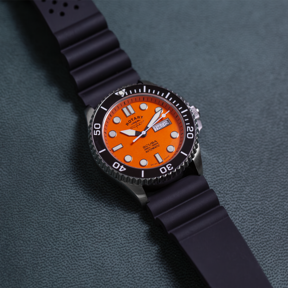 Watch with orange dial and black strap on a textured gray background