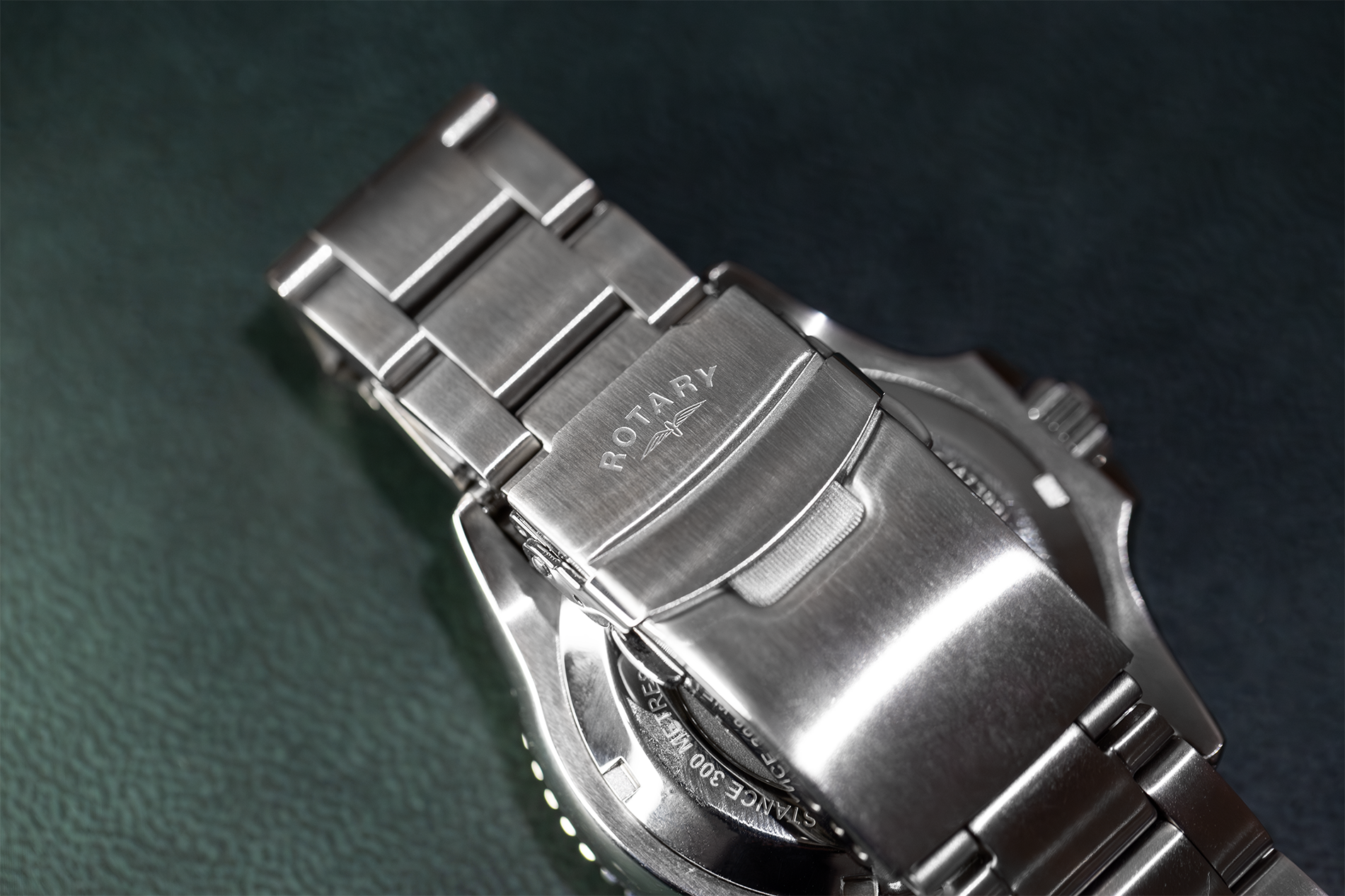 Close-up of a silver rotary watch on a dark textured background