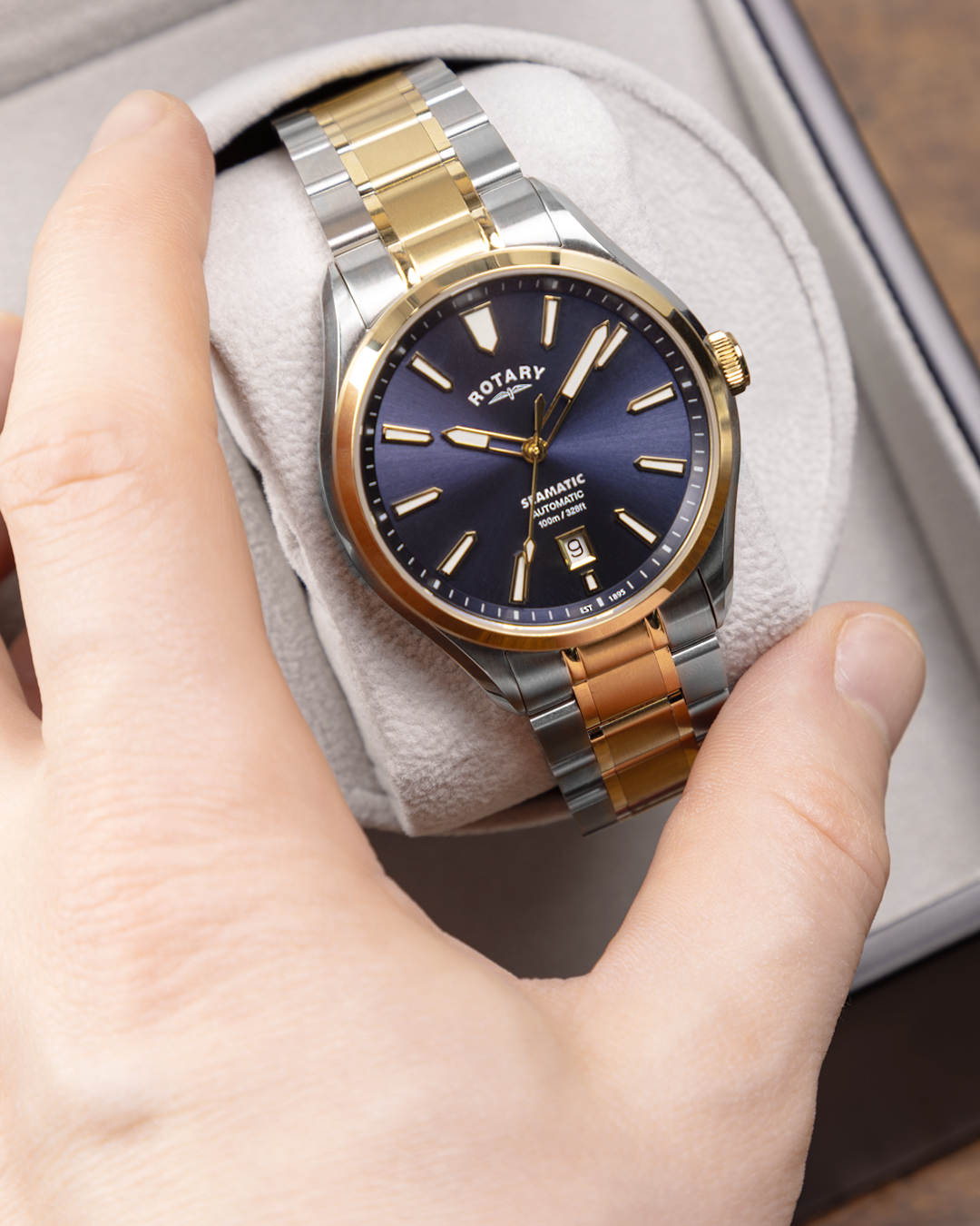 Two-tone Rotary Seamatic 100 watch with blue dial held in a hand