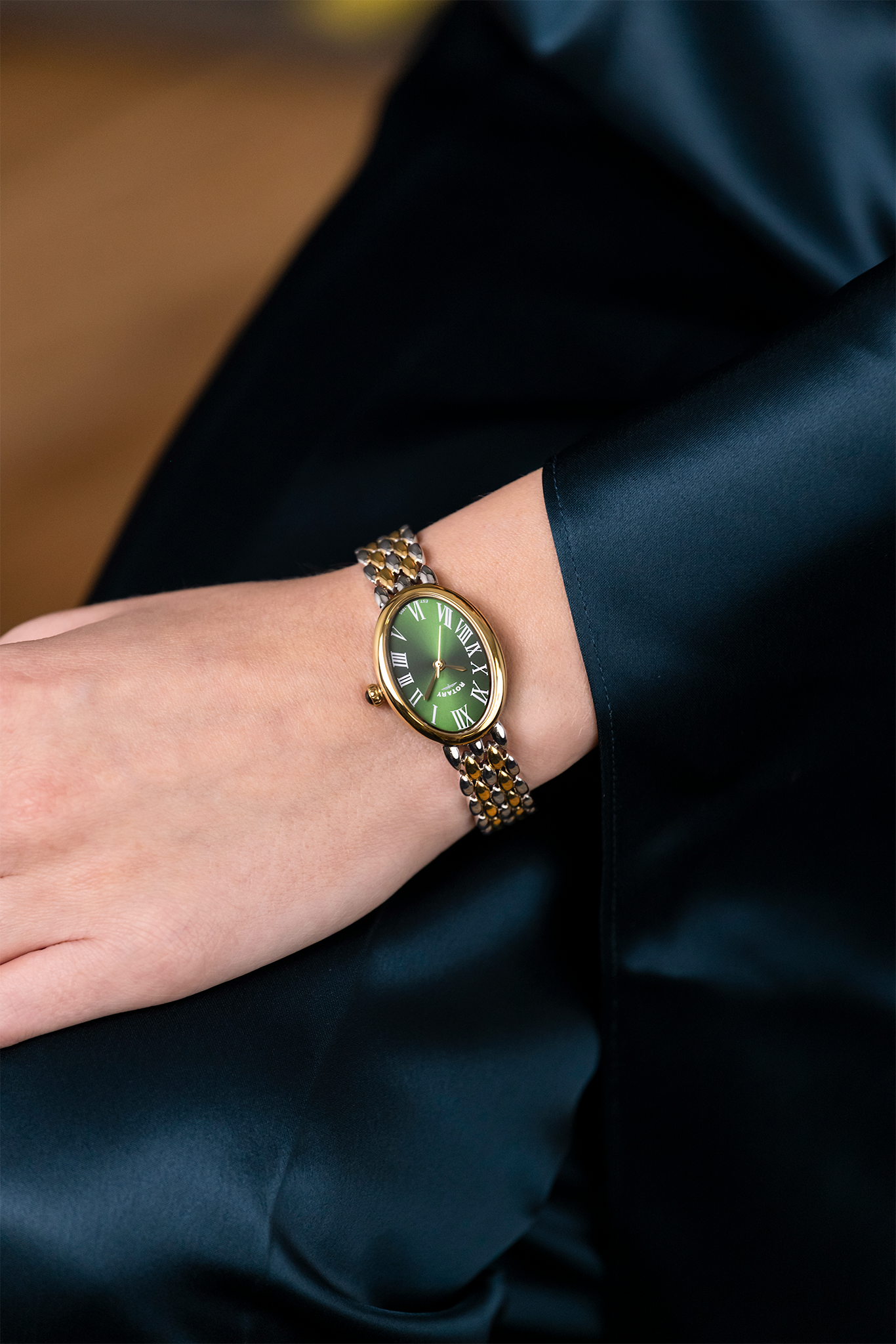 Two tone Rotary Heritage Astoria watch with a green face on a person's wrist against a dark background