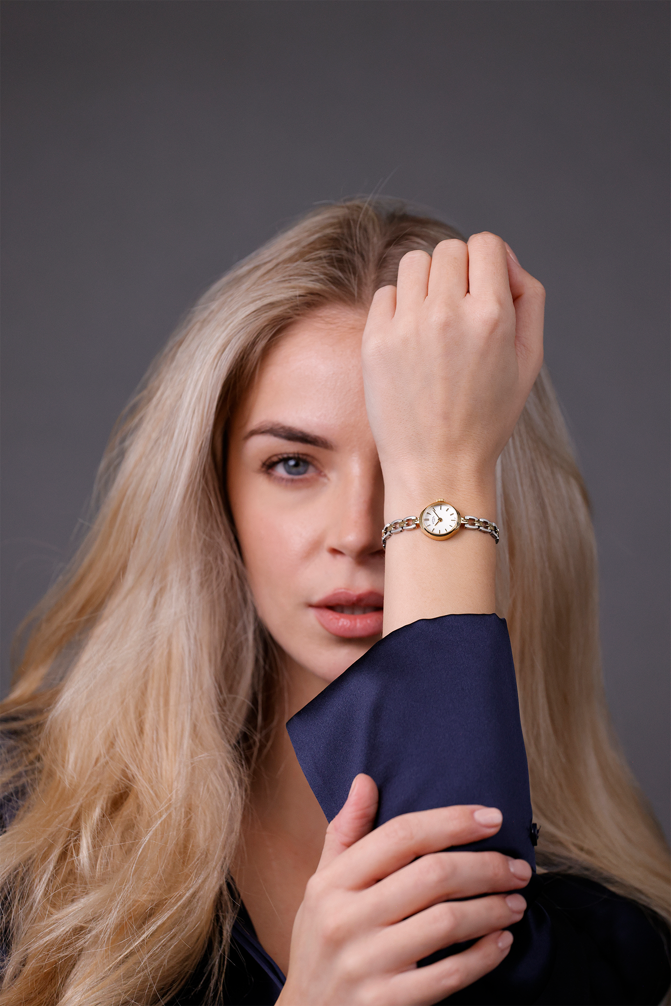 Woman with blonde hair and a Rotary 1895 watch on her wrist against a gray background