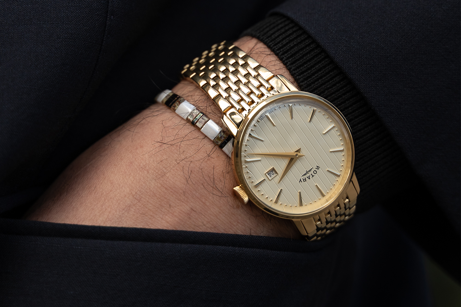Men's gold Rotary wristwatch on a man's wrist with a dark background