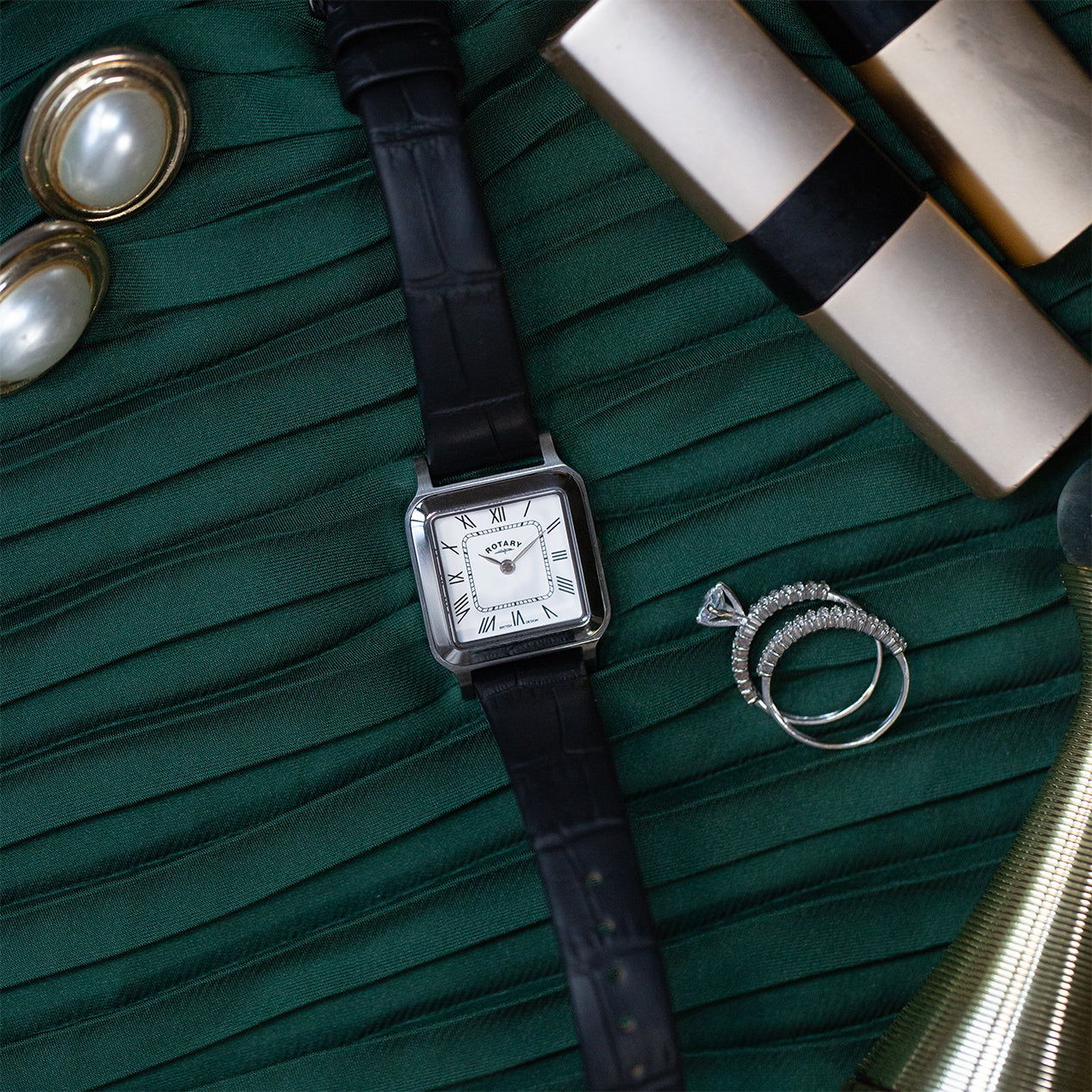 A dressing table with a rotary ladies dress watch in stainless steel surrounded by other items of jewellery