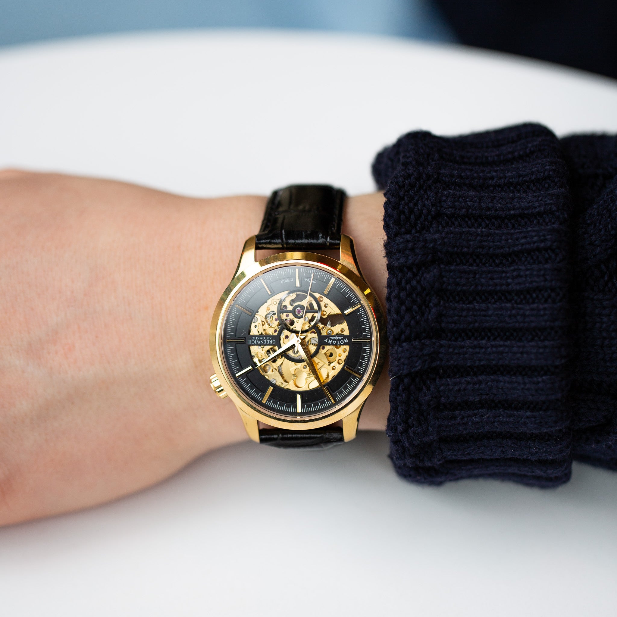 a man wearing a rotary mens skeleton watch in gold with a black leather strap