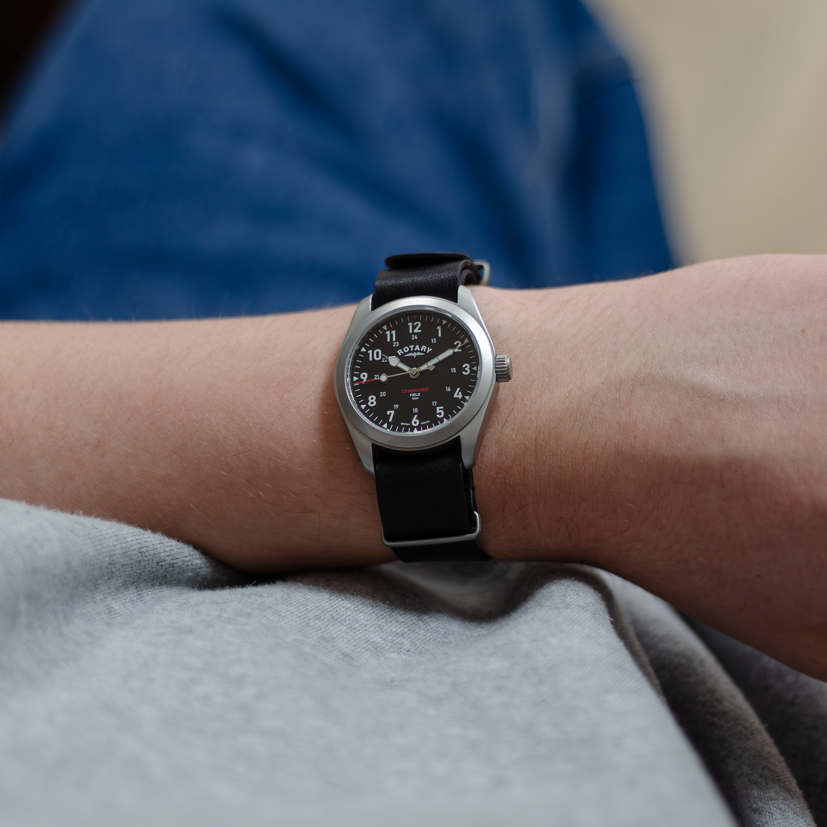 A man dressed in a casual manner wearing a rotary mens watch in stainless steel with a black leather nato strap