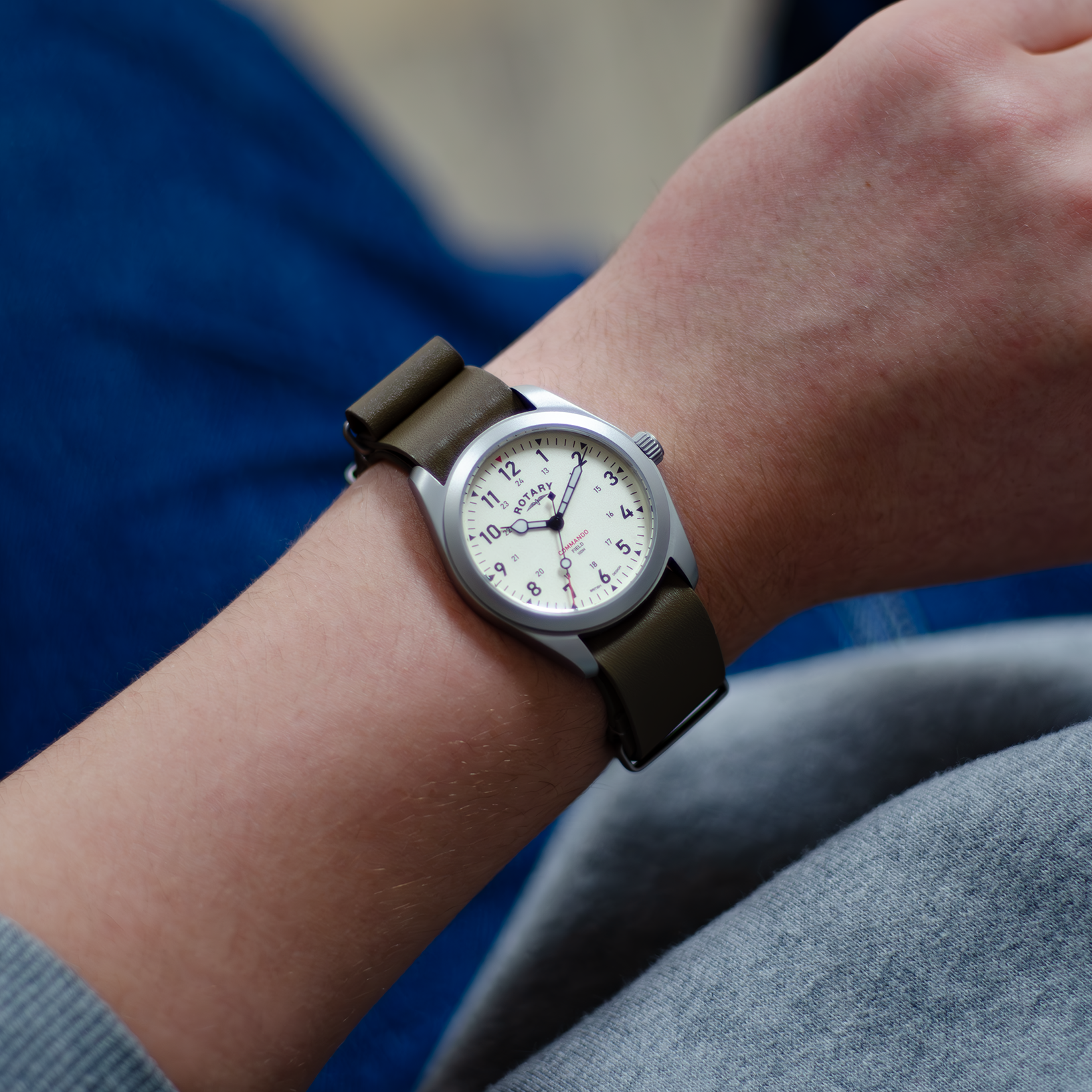 A man dressed in a casual manner wearing a rotary mens watch in stainless steel with a khaki leather nato strap