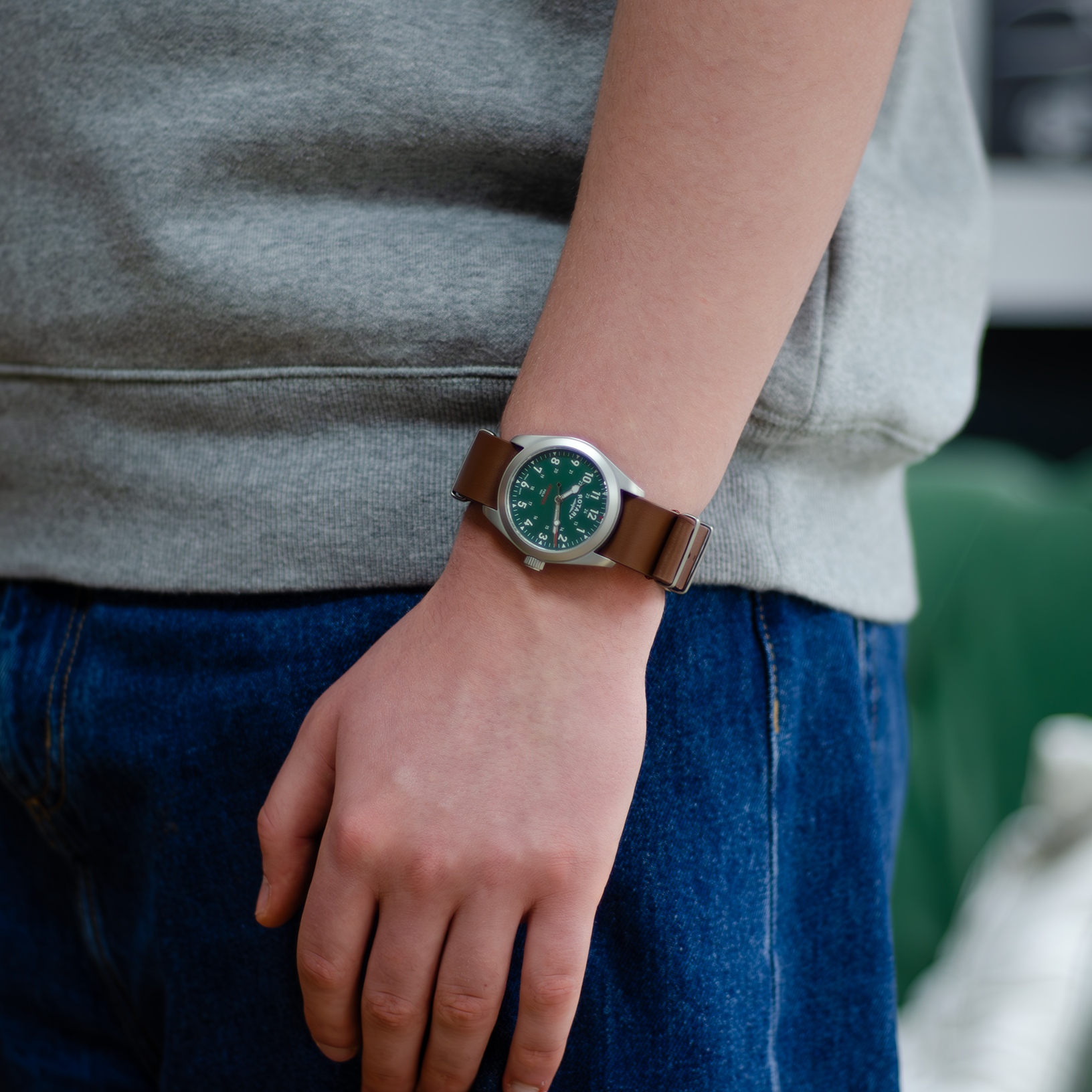 A man dressed in a casual manner wearing a rotary mens watch in stainless steel with a brown leather nato strap