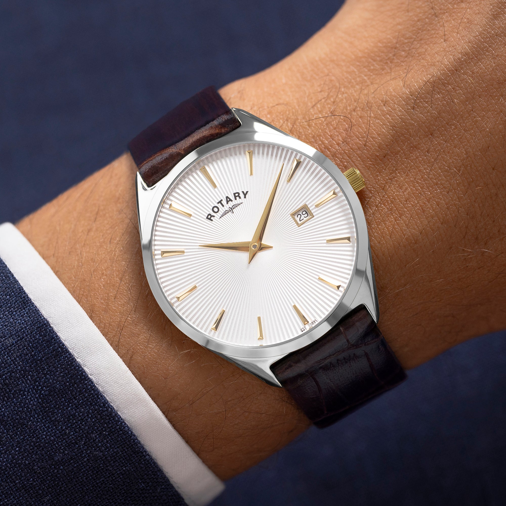 Rotary ultra slim watch on a wrist with a white face and brown leather strap.