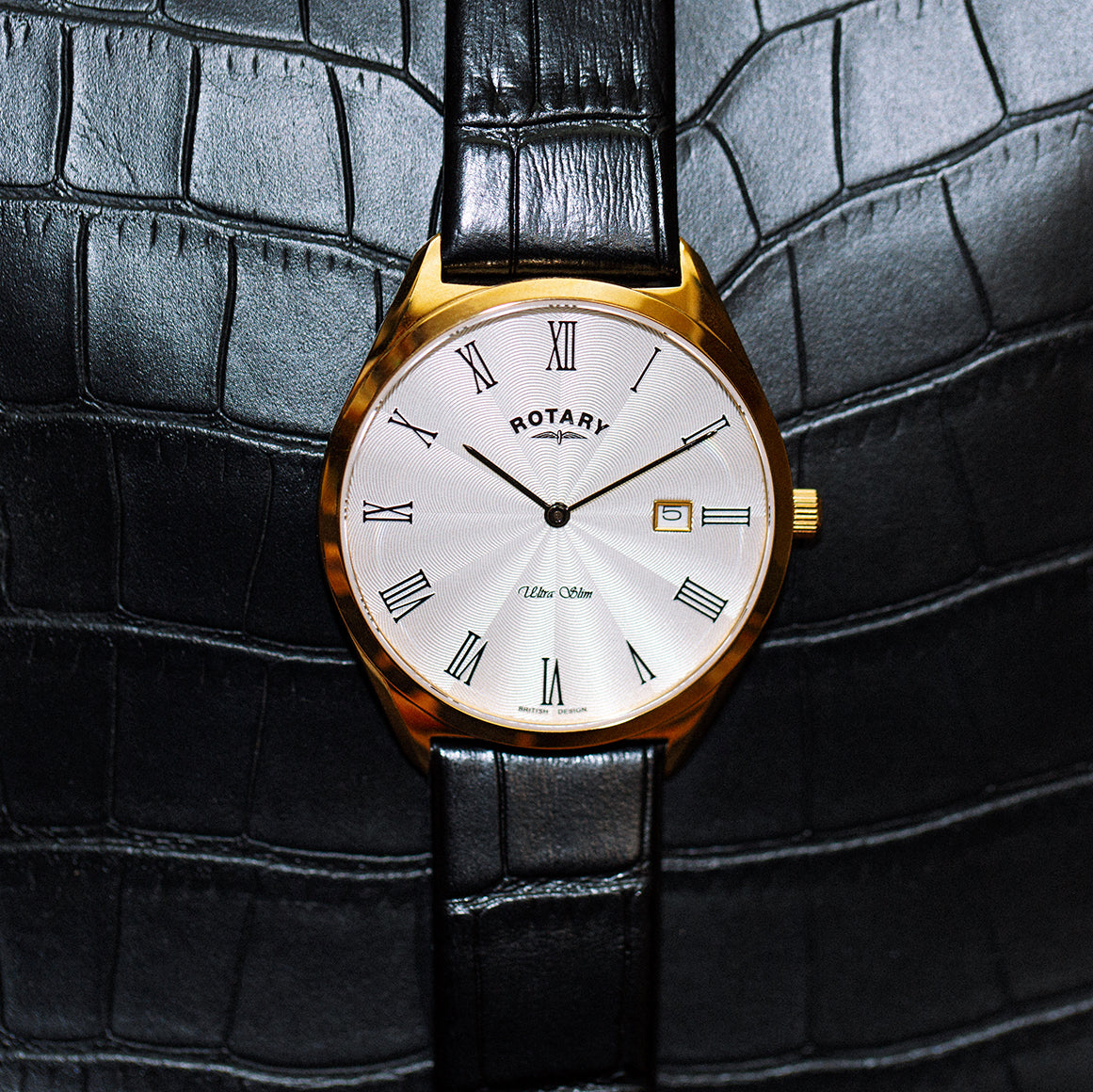 Rotary ultra slim gold watch rested on a leather bag