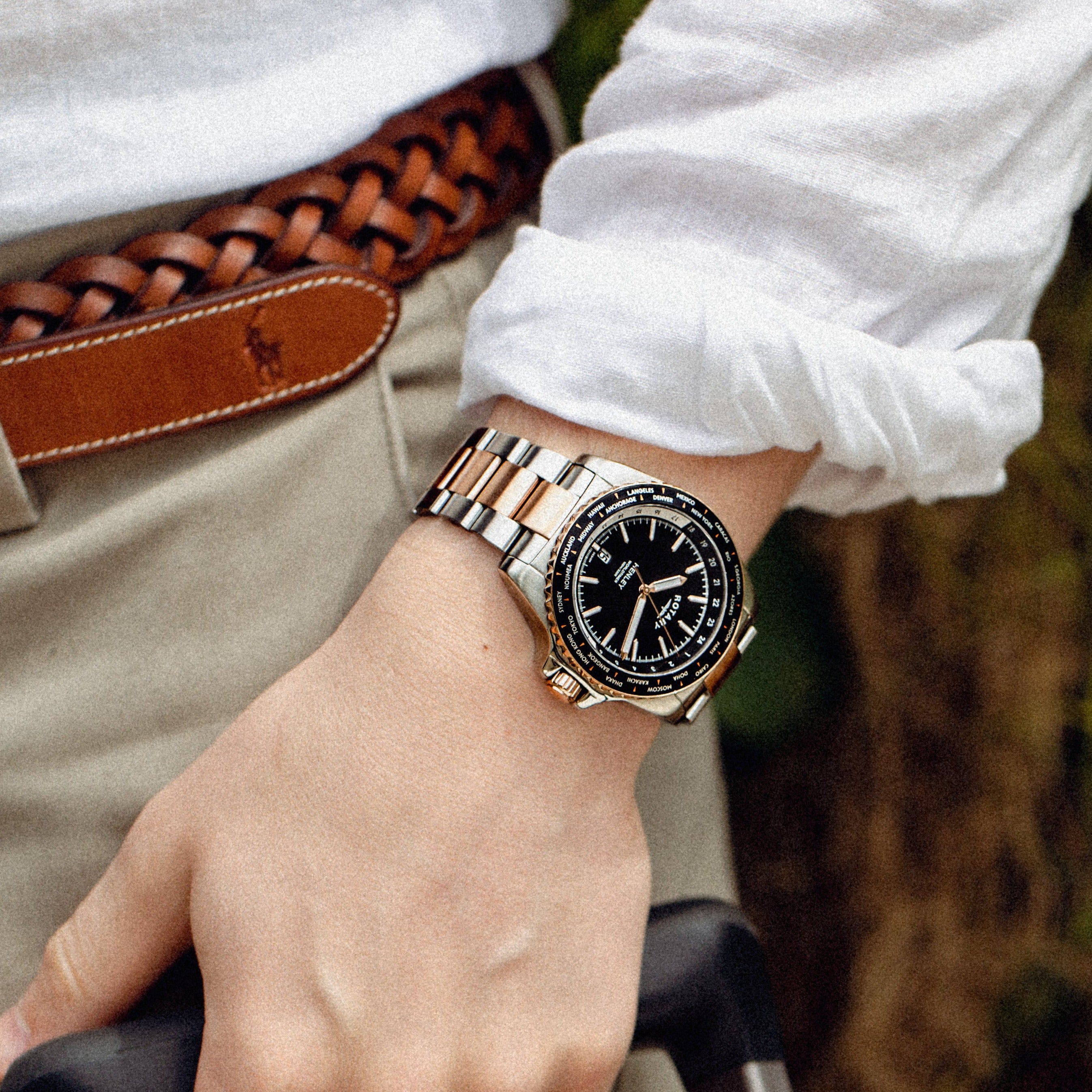 A man with a white shirt wearing a two-tone stainless steel and rose gold rotary watch with a black dial.