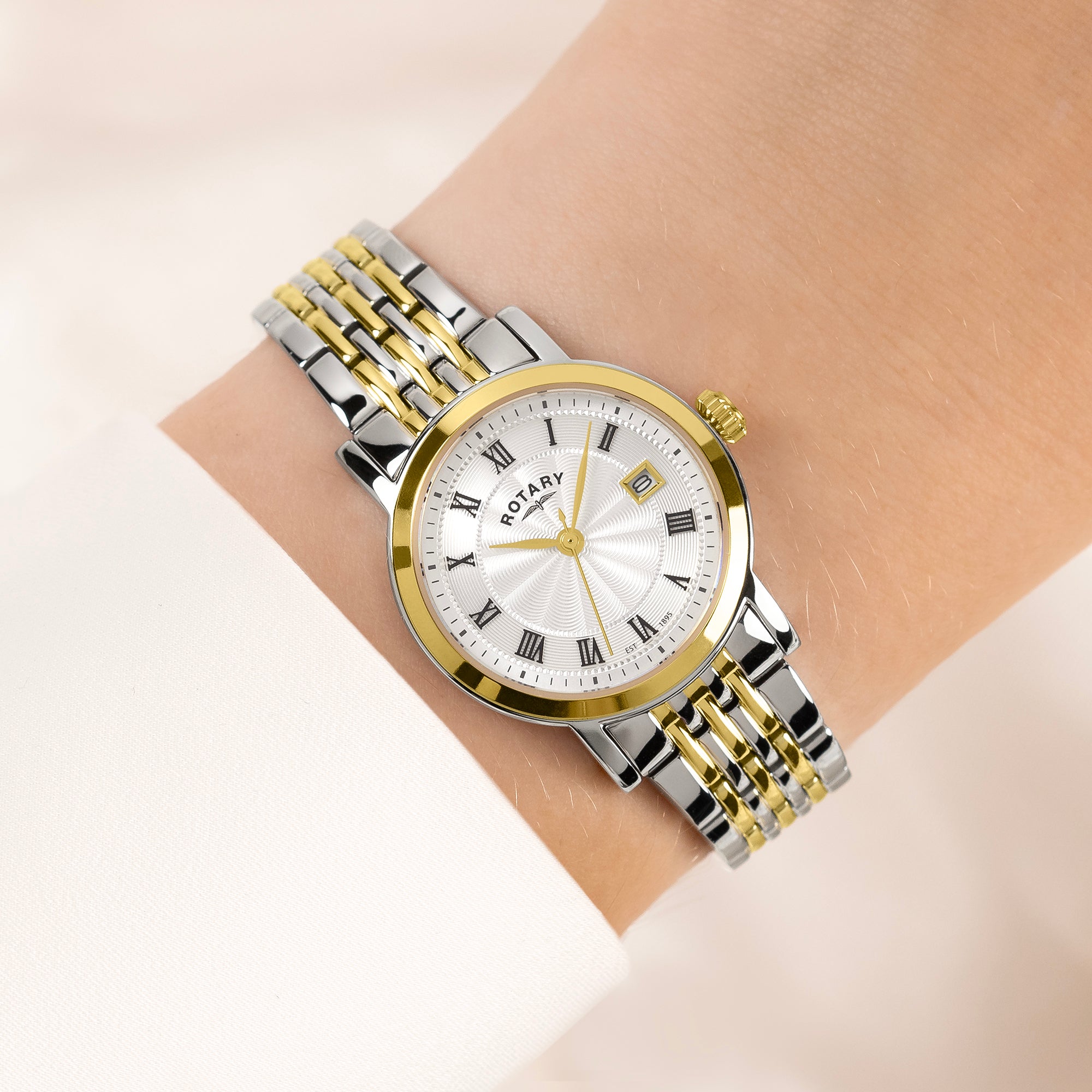 Two-tone Rotary watch with silver and gold band on a wrist against a light background