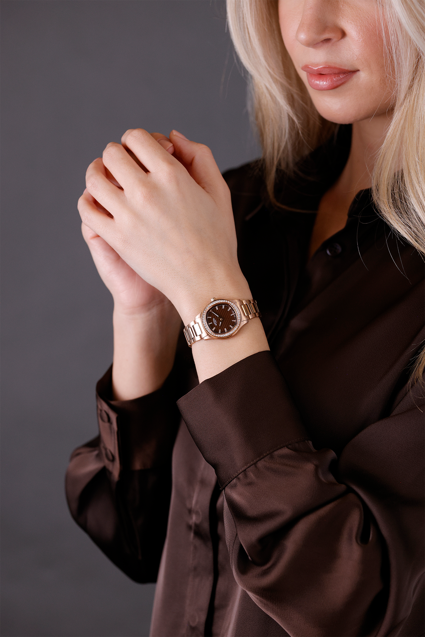 Woman wearing a rose gold Rotary Brilliance watch on a gray background