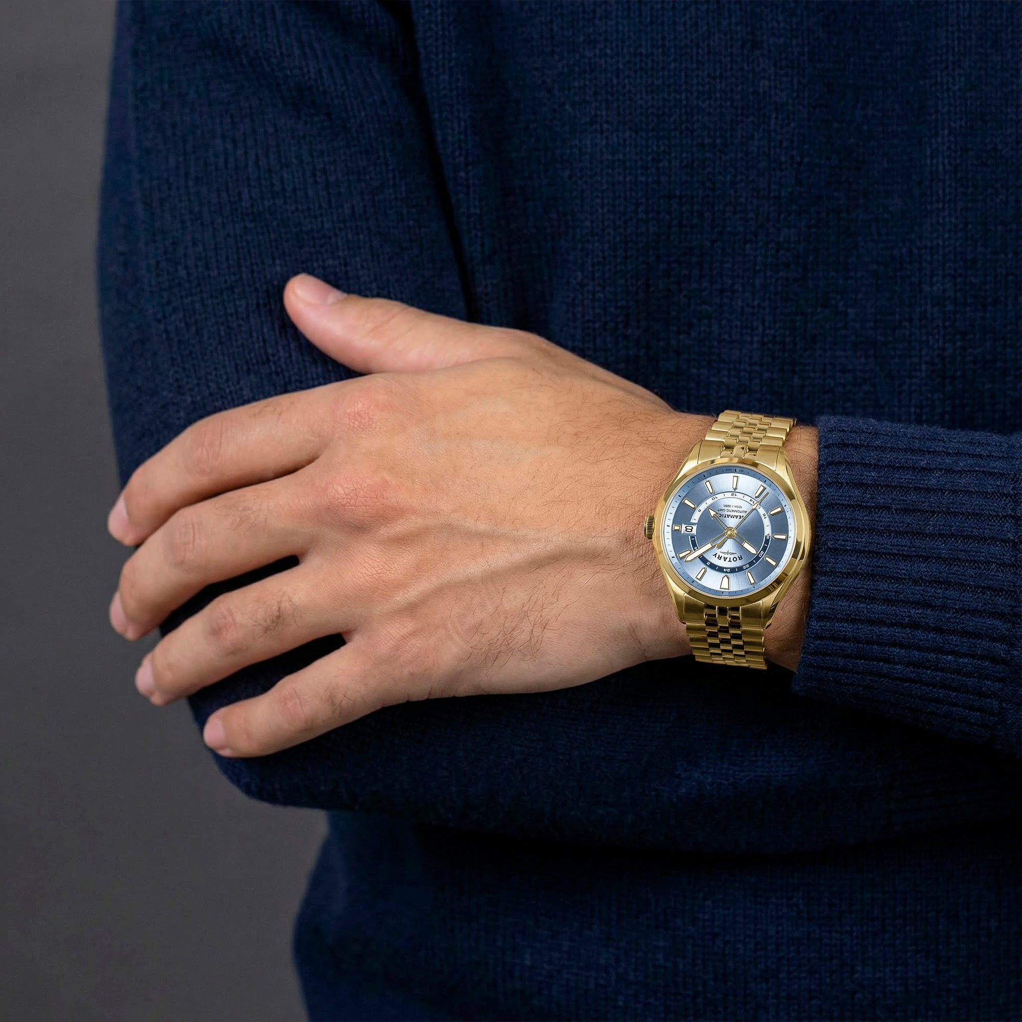 Gold Rotary Seamatic 100  GMT watch on a man's wrist with a dark blue sweater