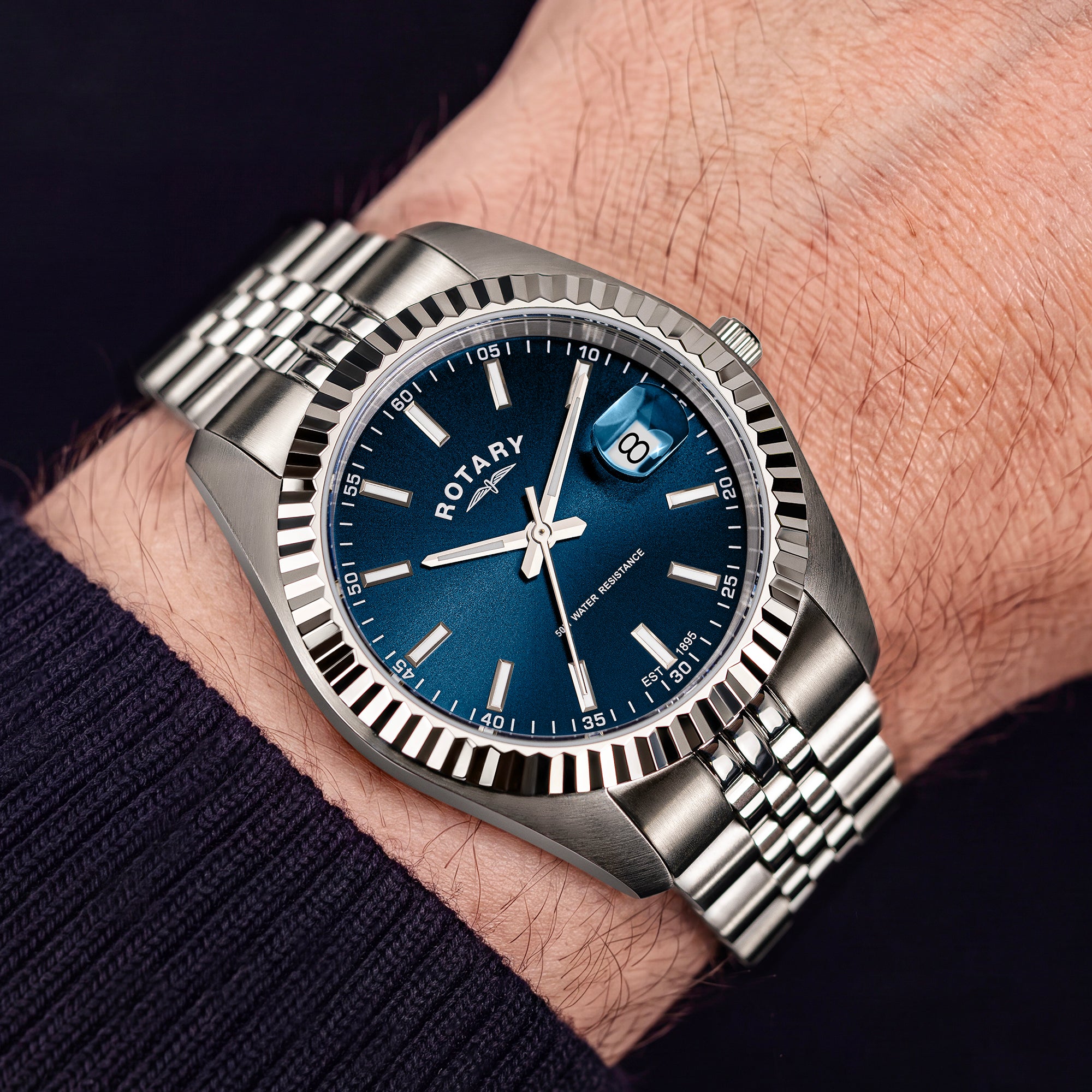 A close-up of a wrist wearing a Rotary watch with a blue dial and a silver stainless steel bracelet.