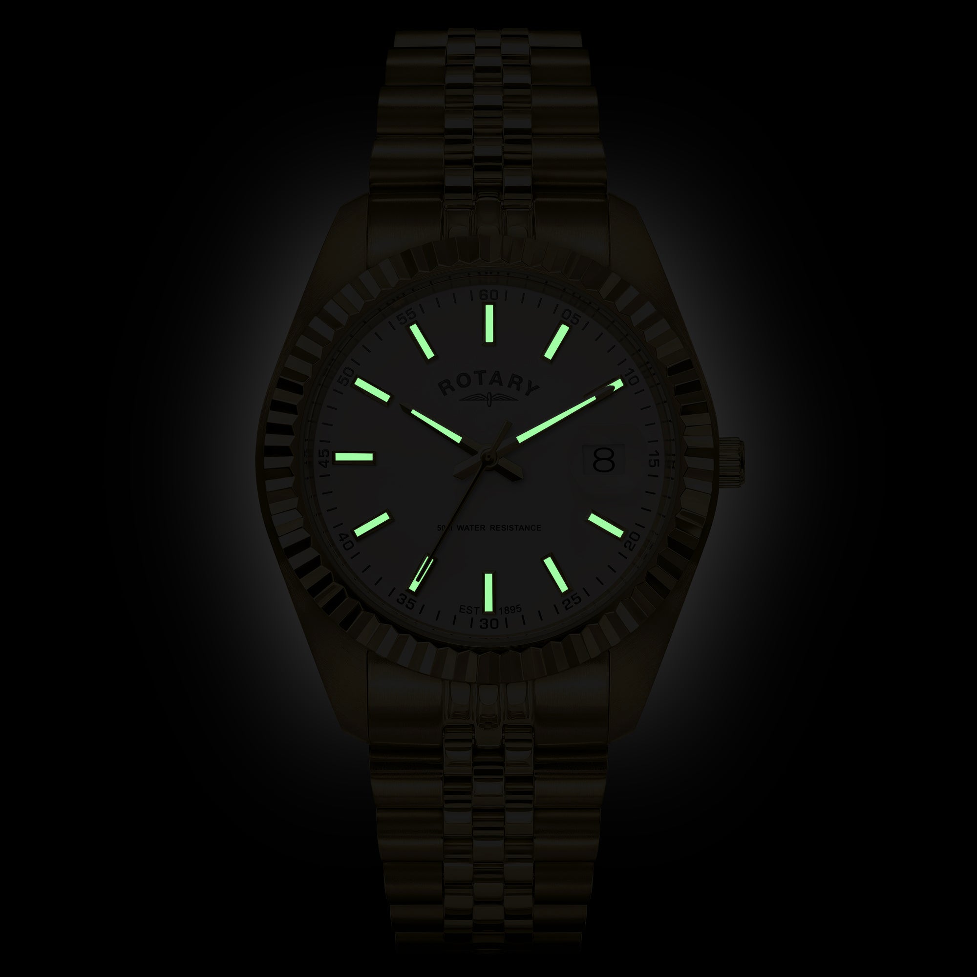 A gold Rotary watch with a matching link bracelet, featuring glowing green luminescent hour markers and hands on a white dial, shown against a dark background.