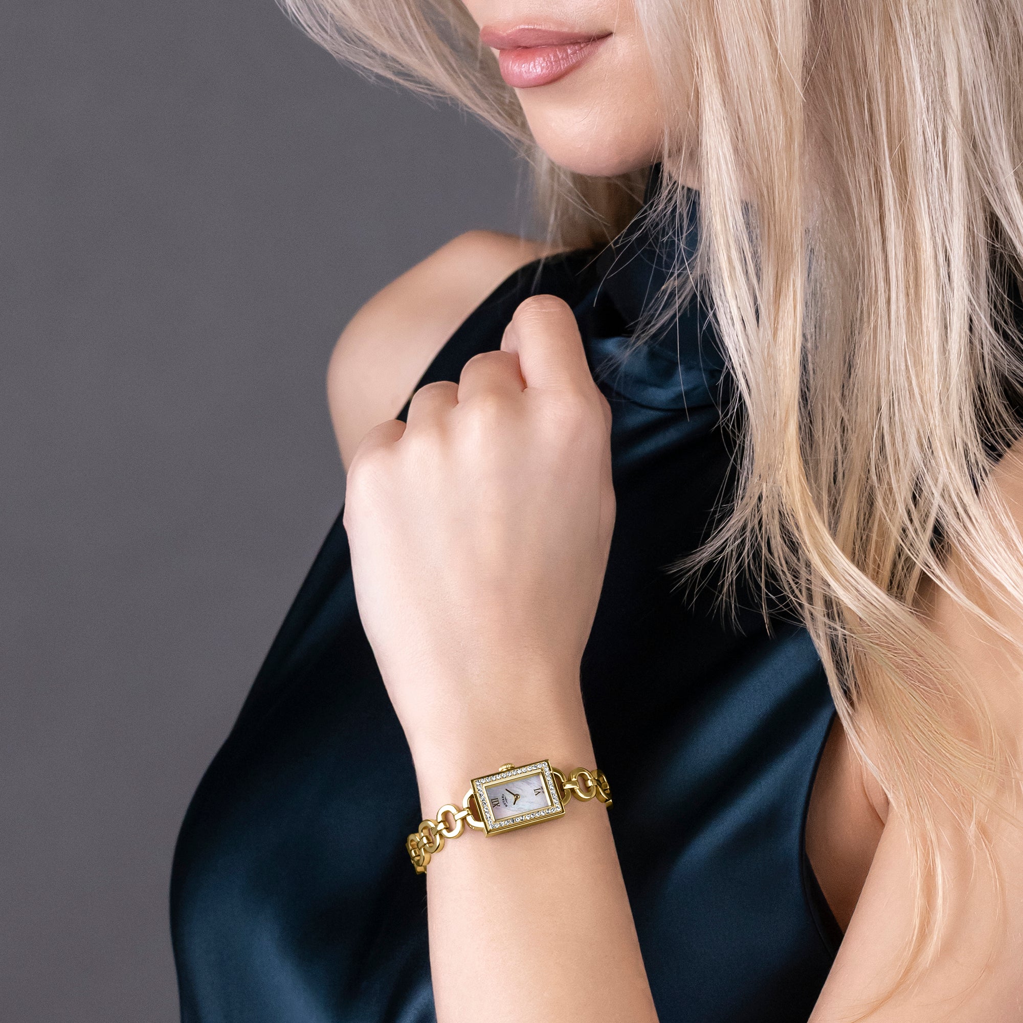 Woman wearing a gold bracelet Rotary Watch with a mother of pearl face on a dark background